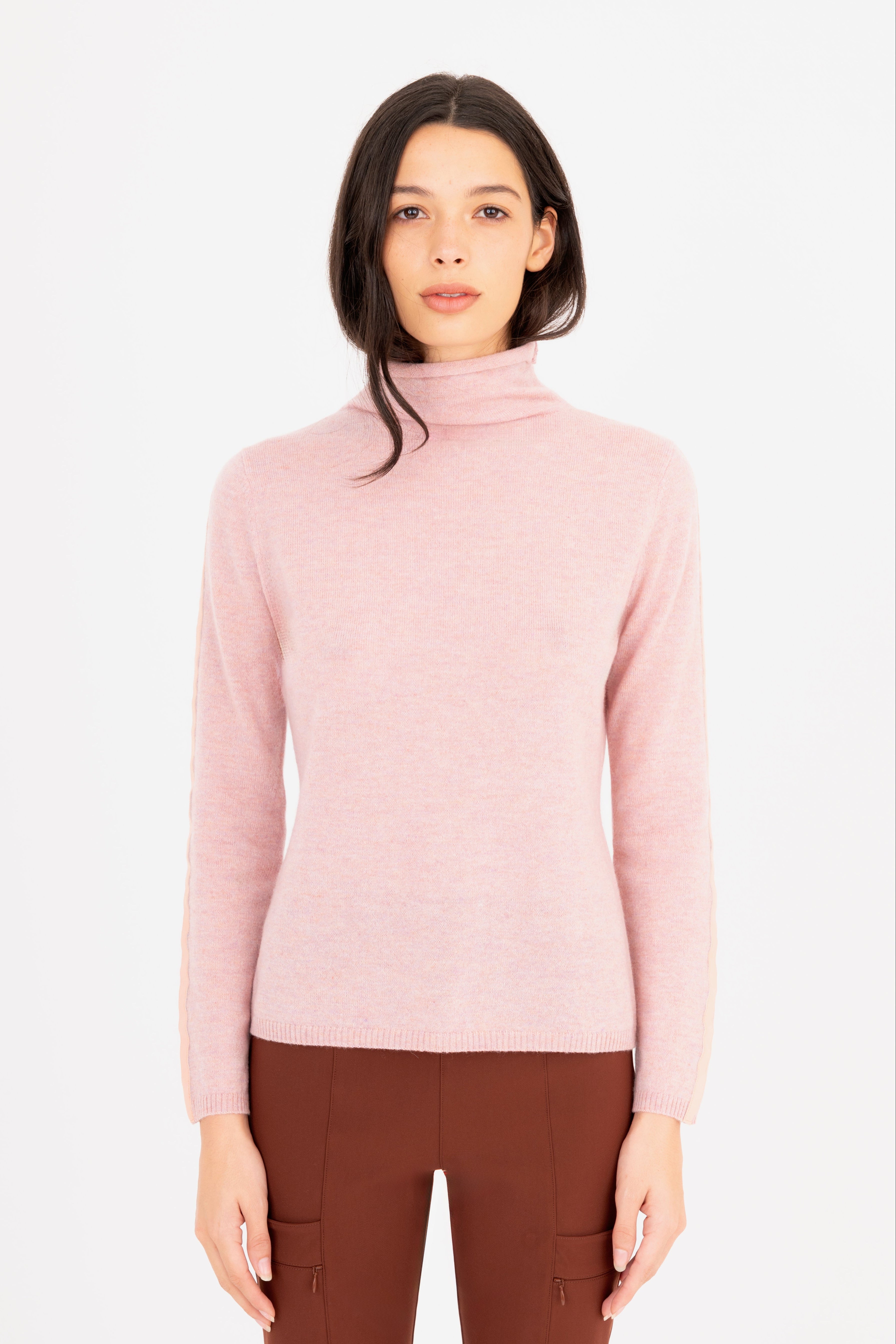 Woman wearing a light pink turtleneck sweater on a white background