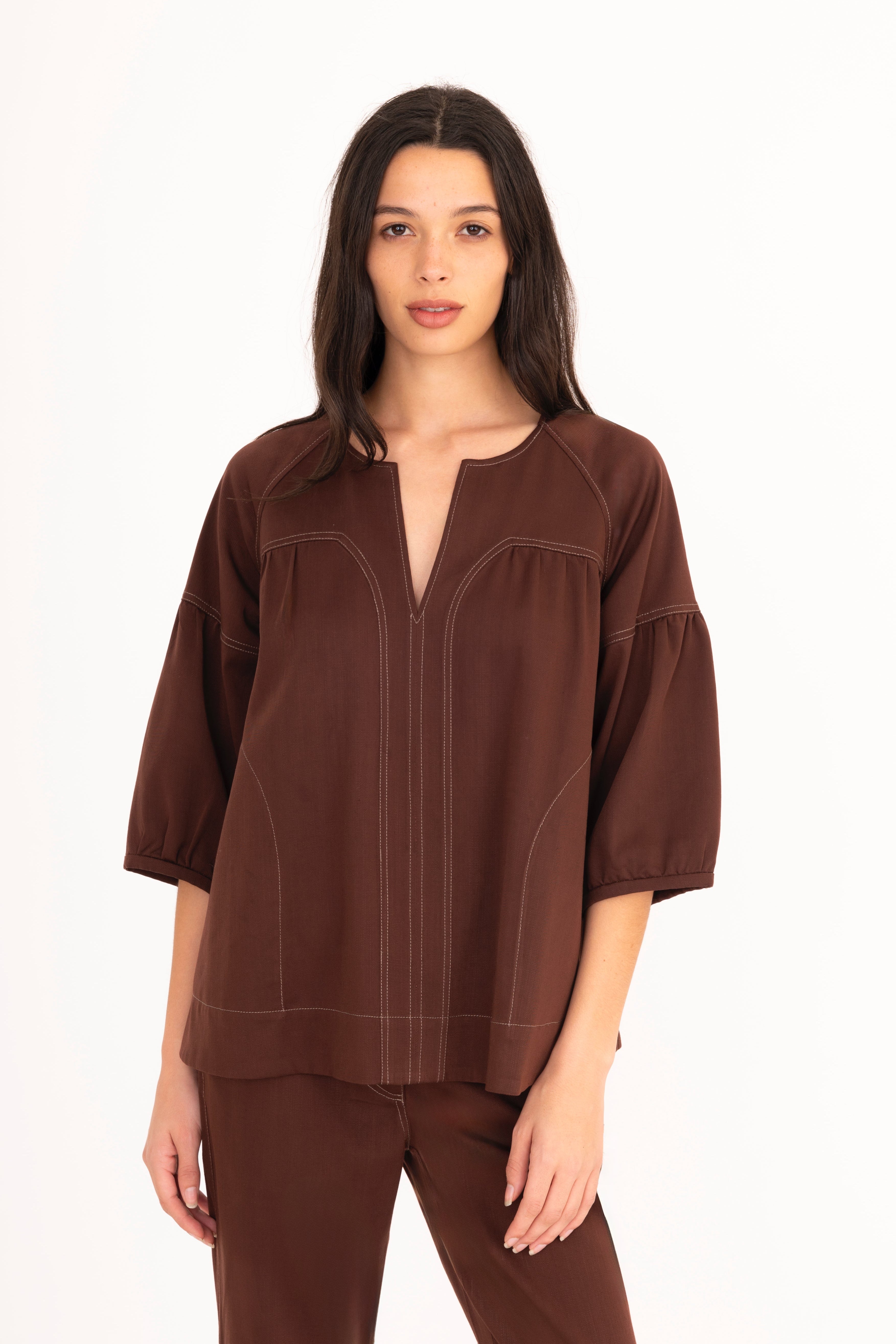 Woman wearing a brown blouse and pants on a white background