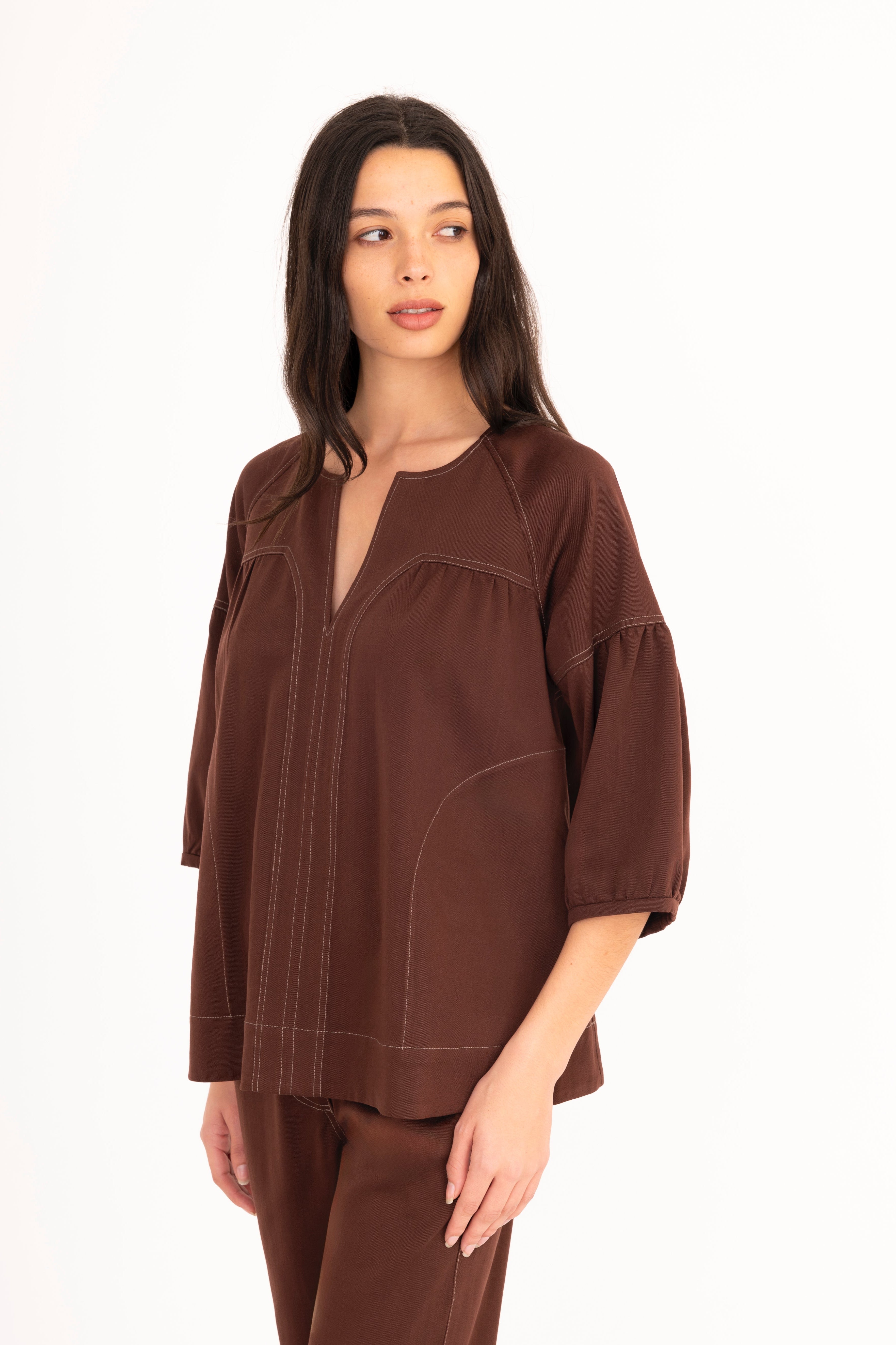 Woman wearing a brown blouse and pants on a white background