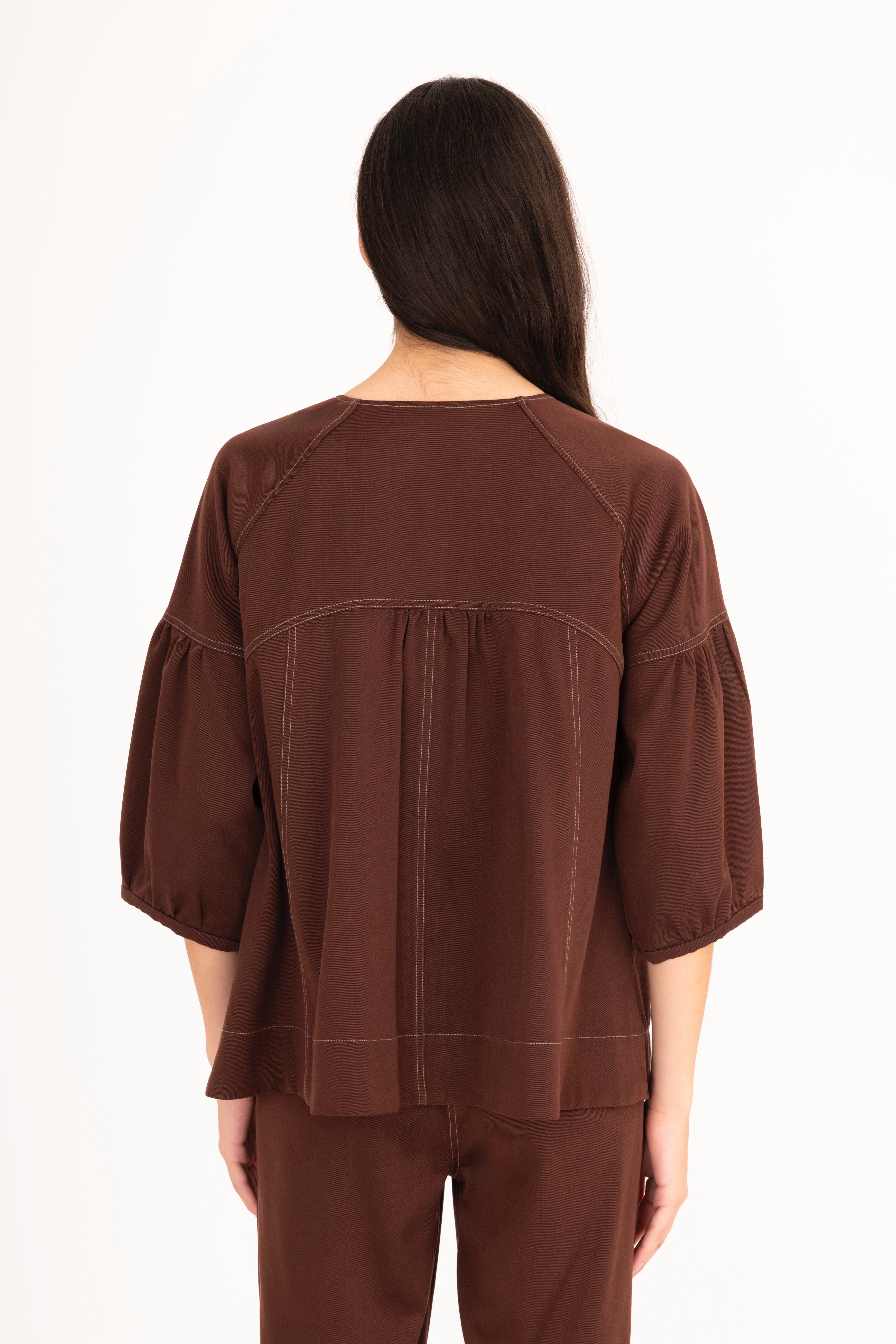 Woman wearing a brown blouse and pants on a white background