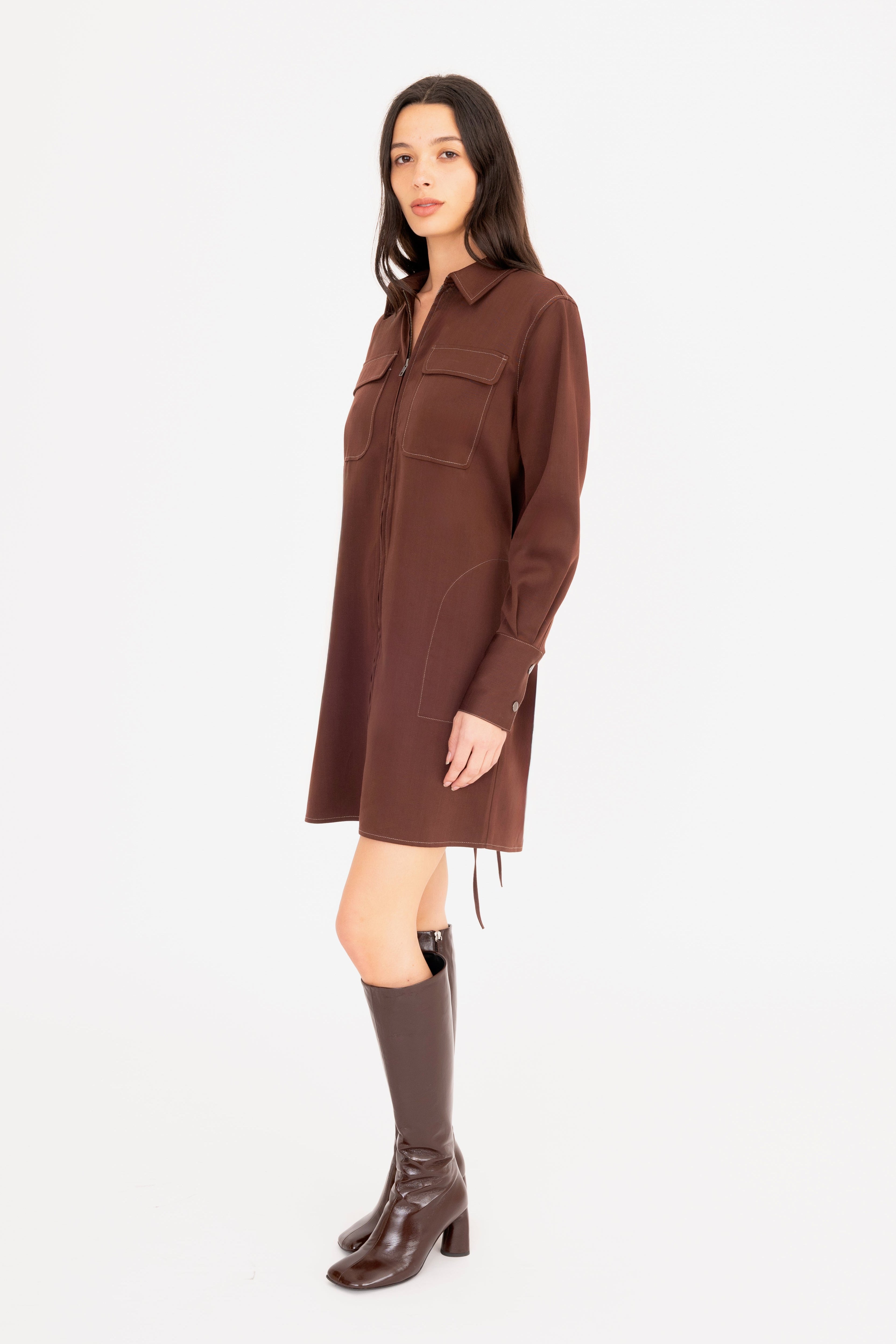 Woman wearing a brown dress with long sleeves on a white background
