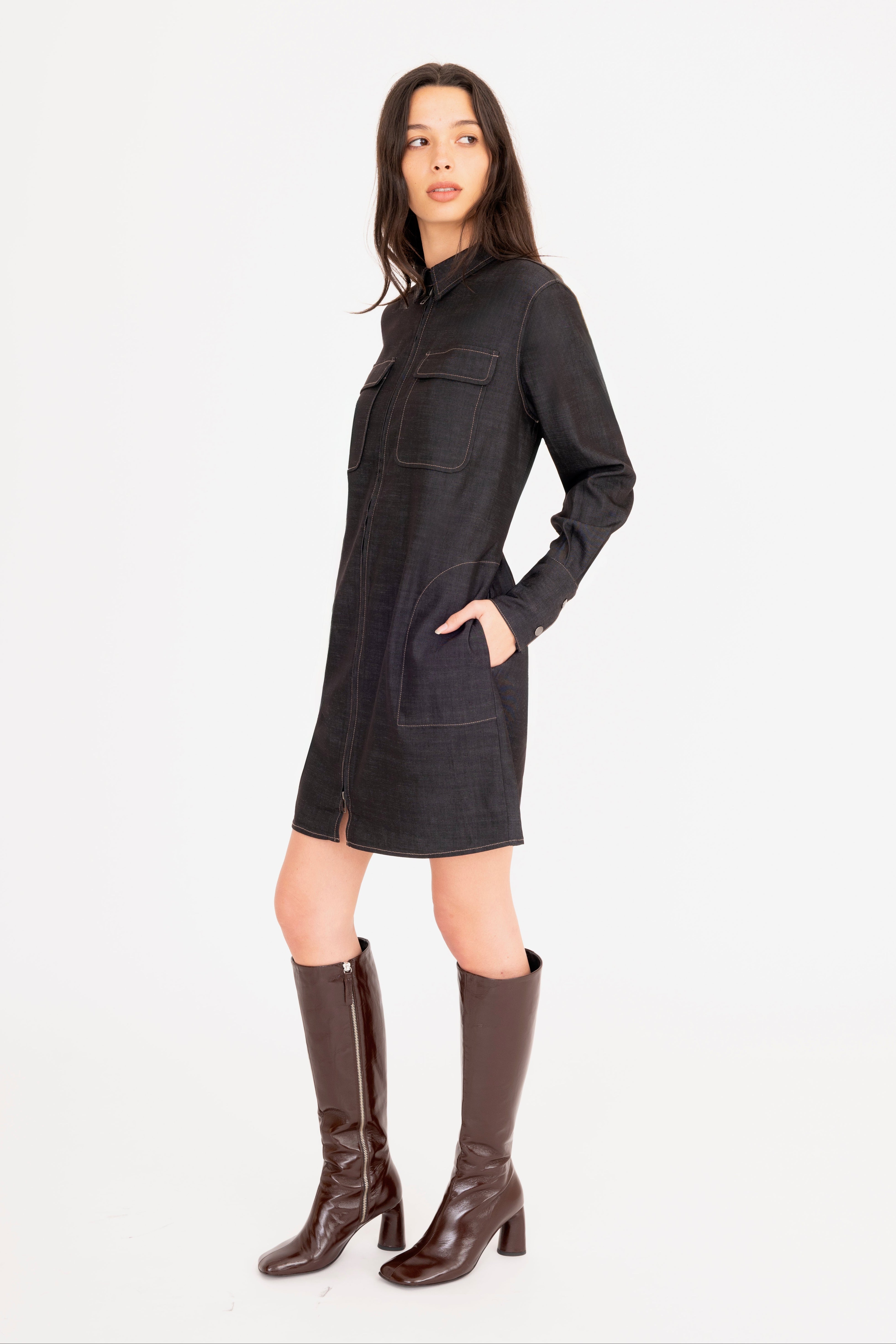 Woman wearing a black dress with brown boots on a white background