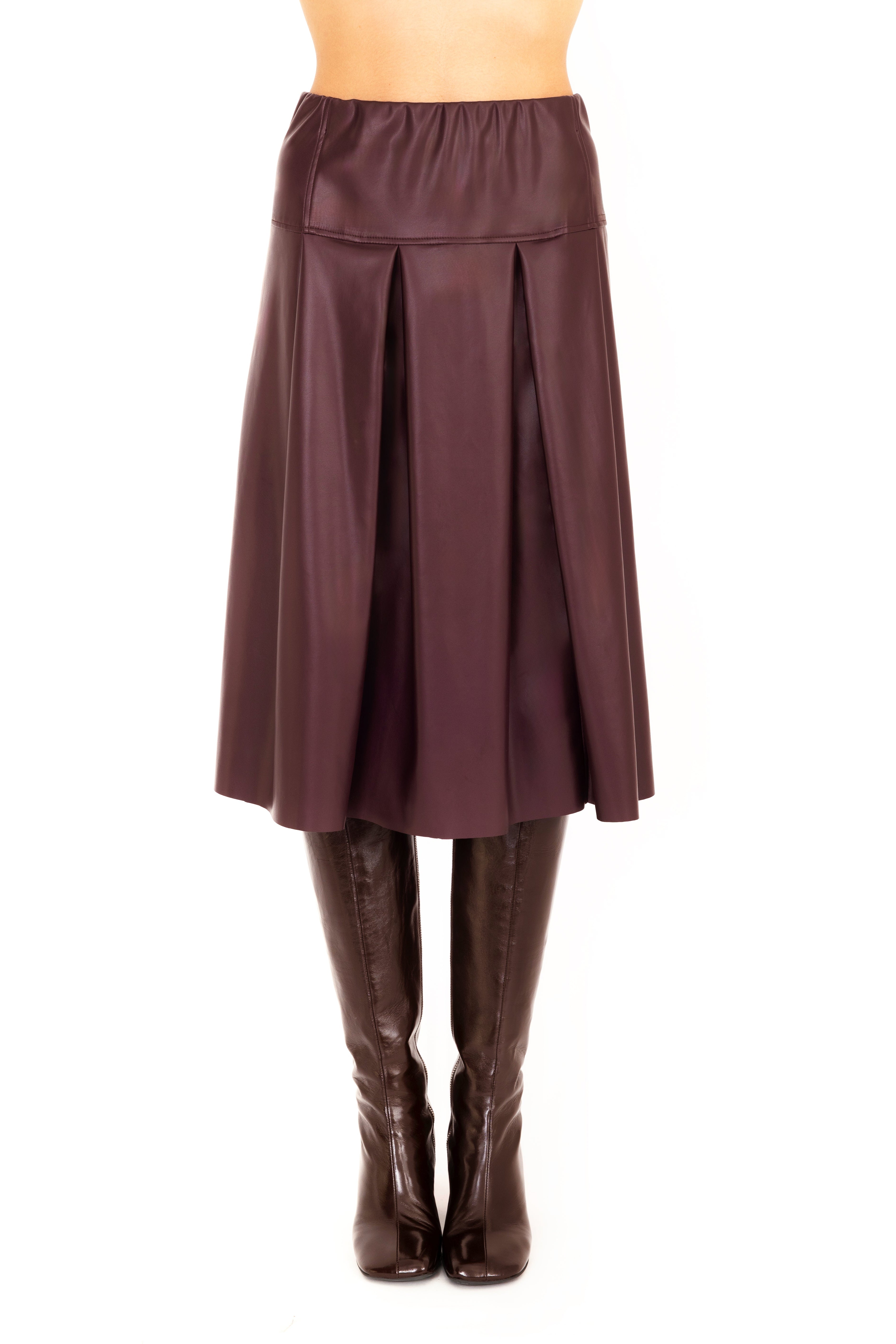 Person wearing a burgundy skirt and brown knee-high boots on a white