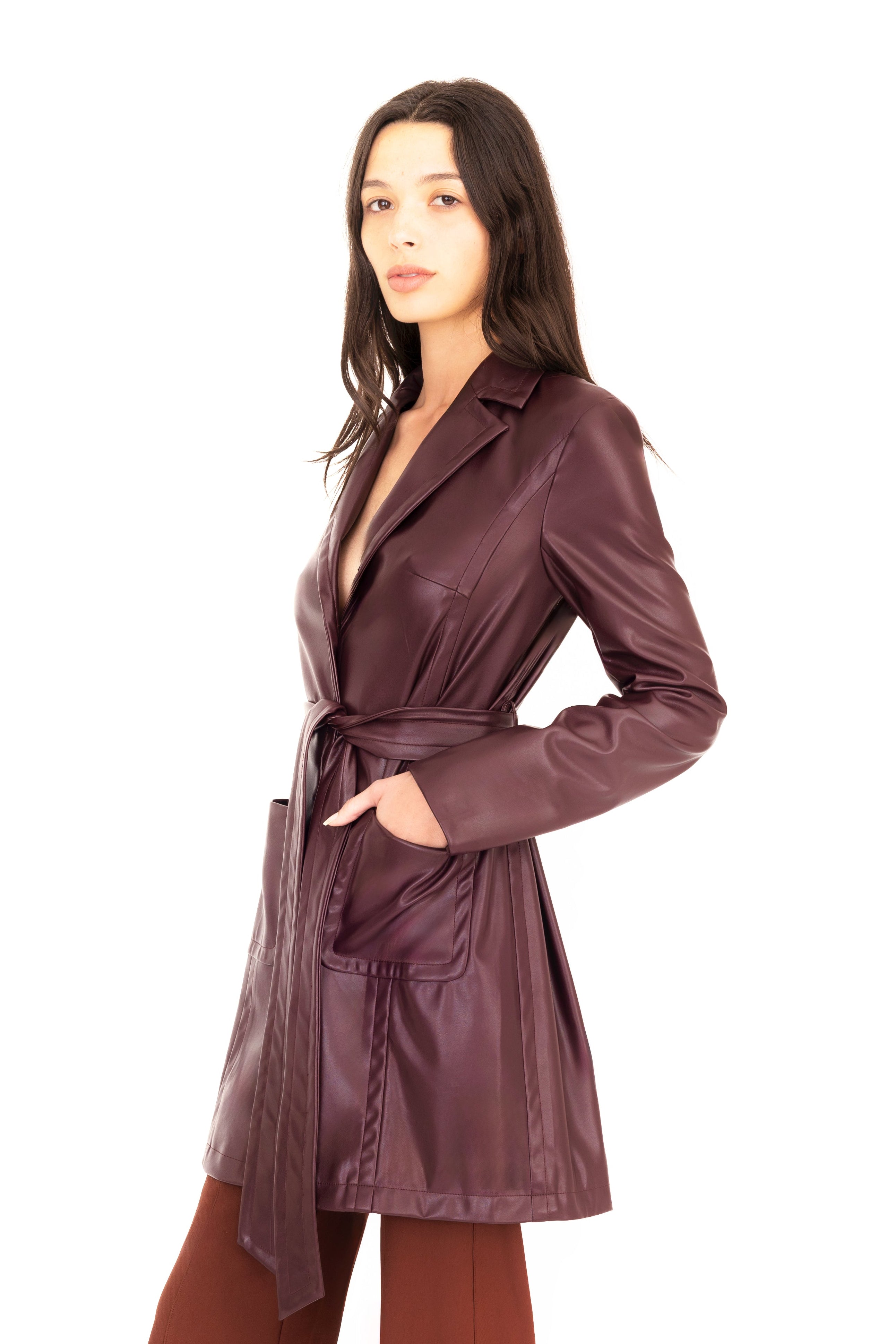 Woman wearing a burgundy trench coat and pants on a white