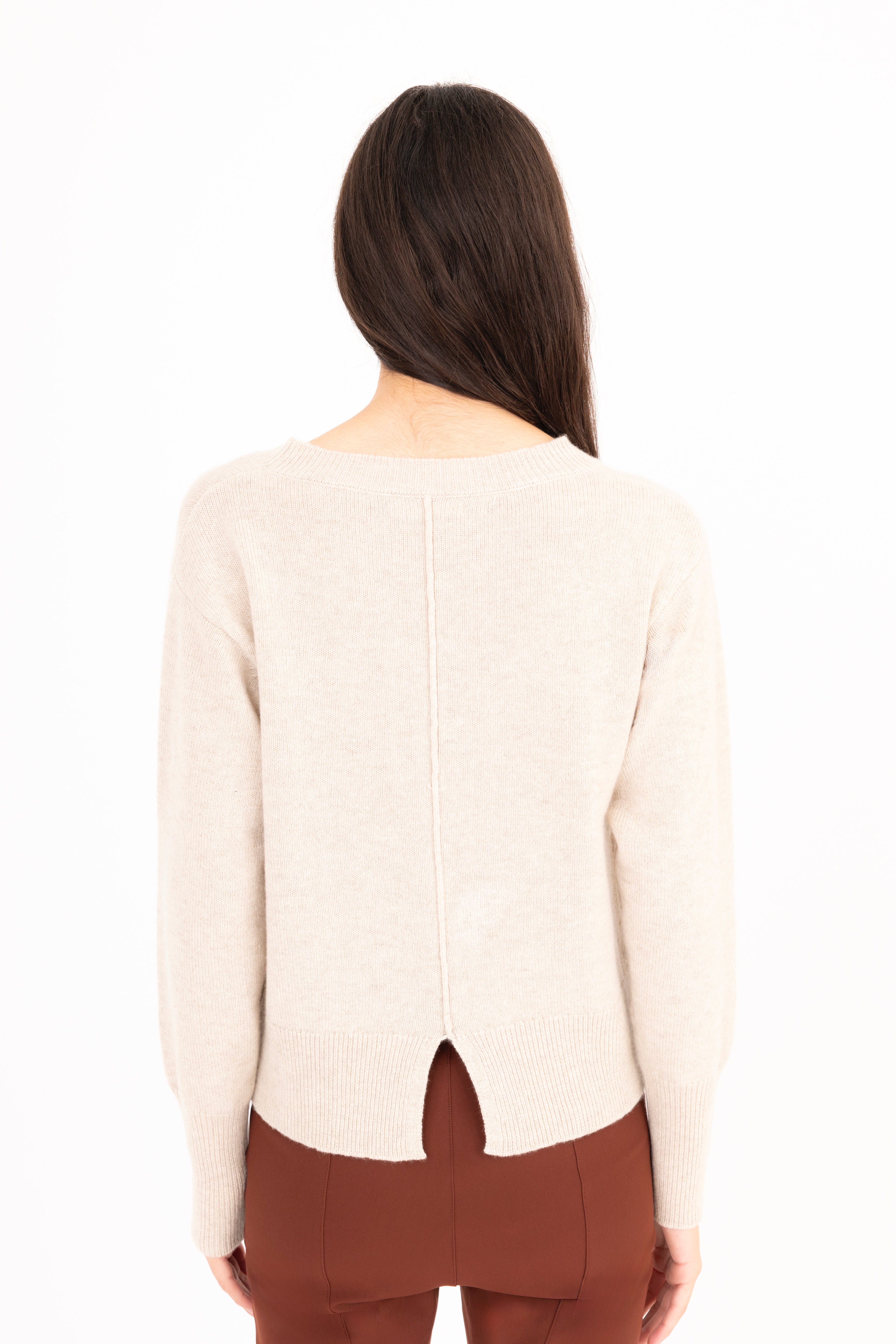 Woman wearing a beige sweater and brown pants on a white background