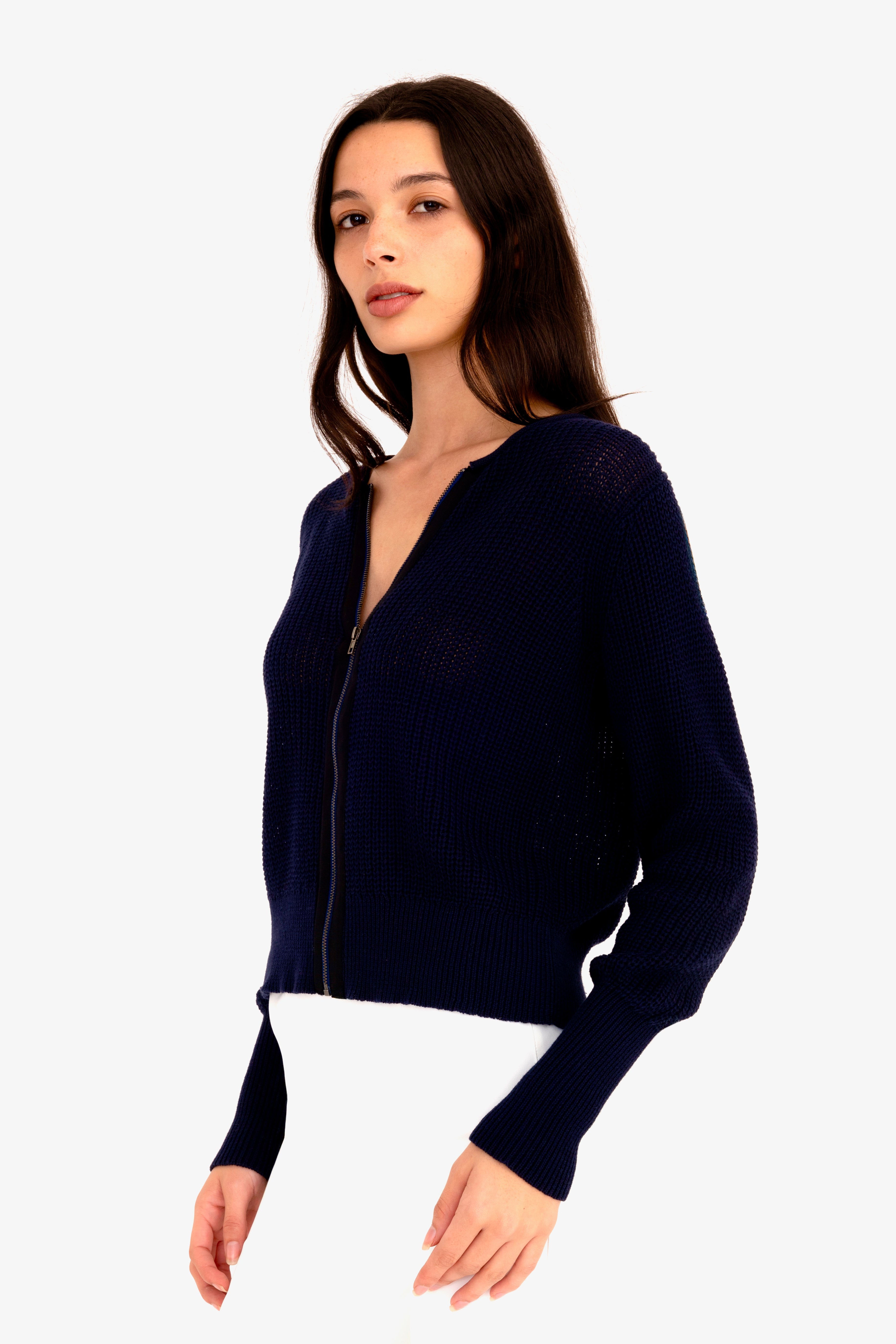 Woman wearing a navy blue zip-up sweater on a white background