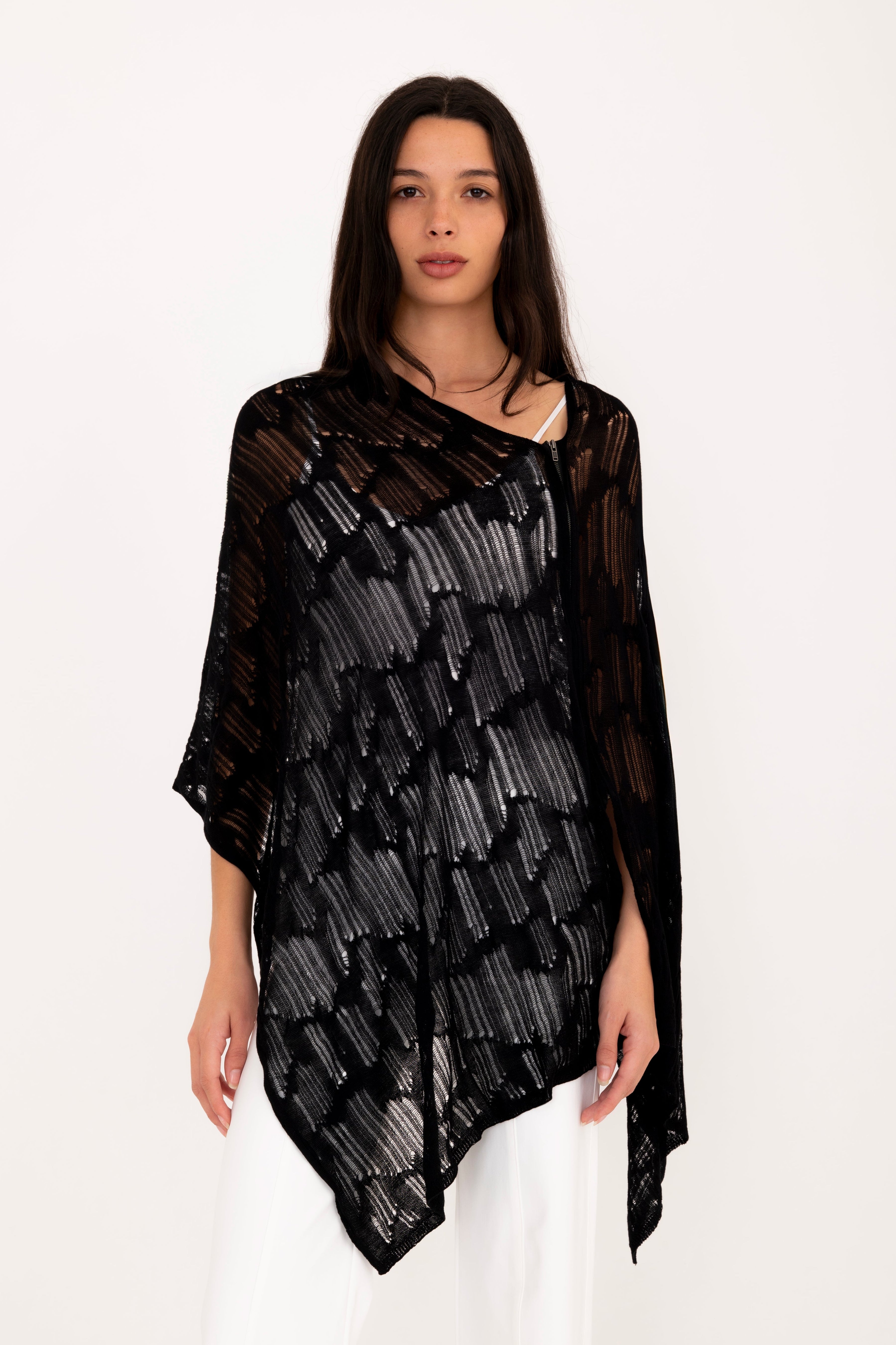 Woman wearing a black poncho top on a white background