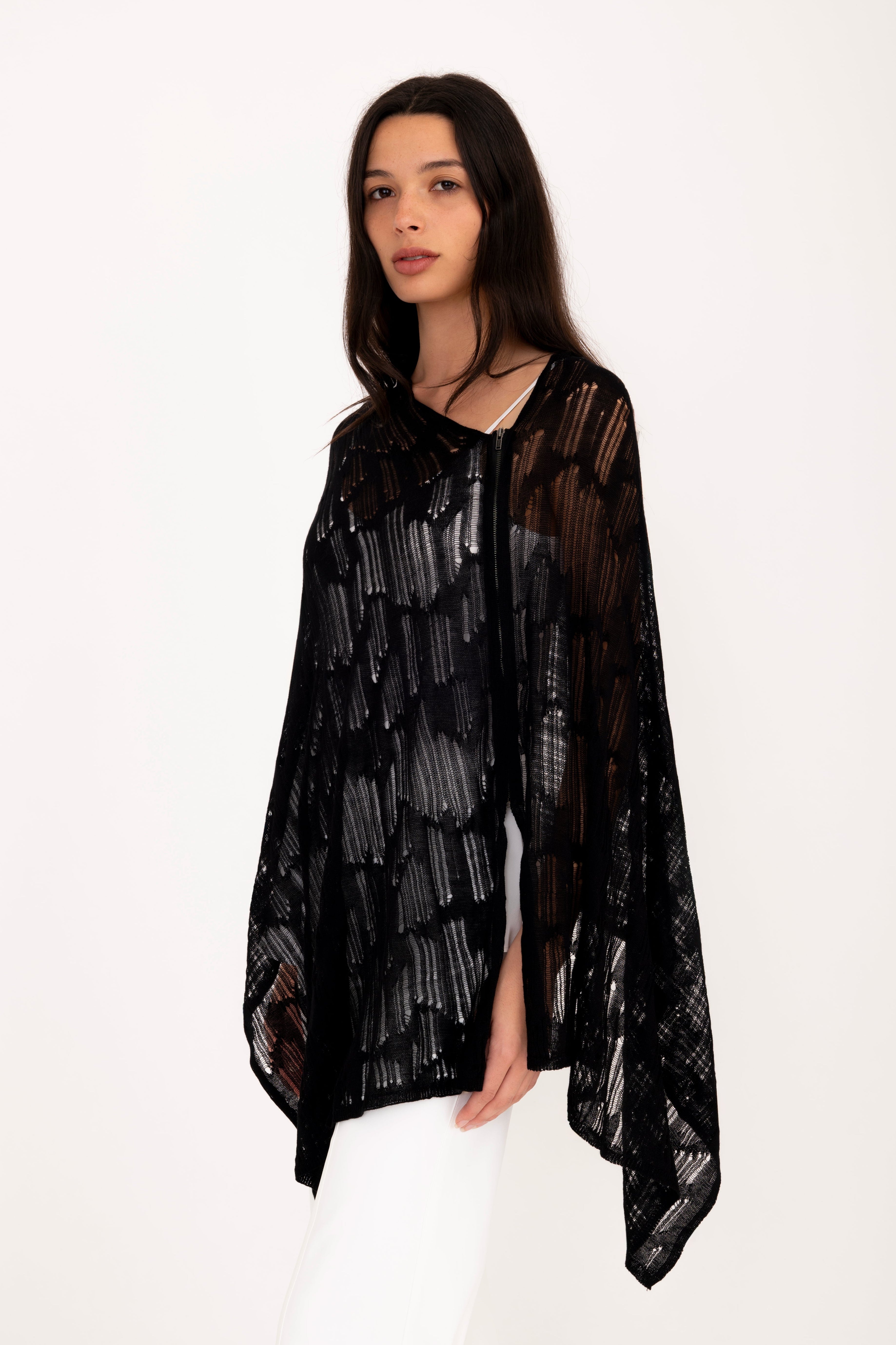 Woman wearing a black poncho top on a white background