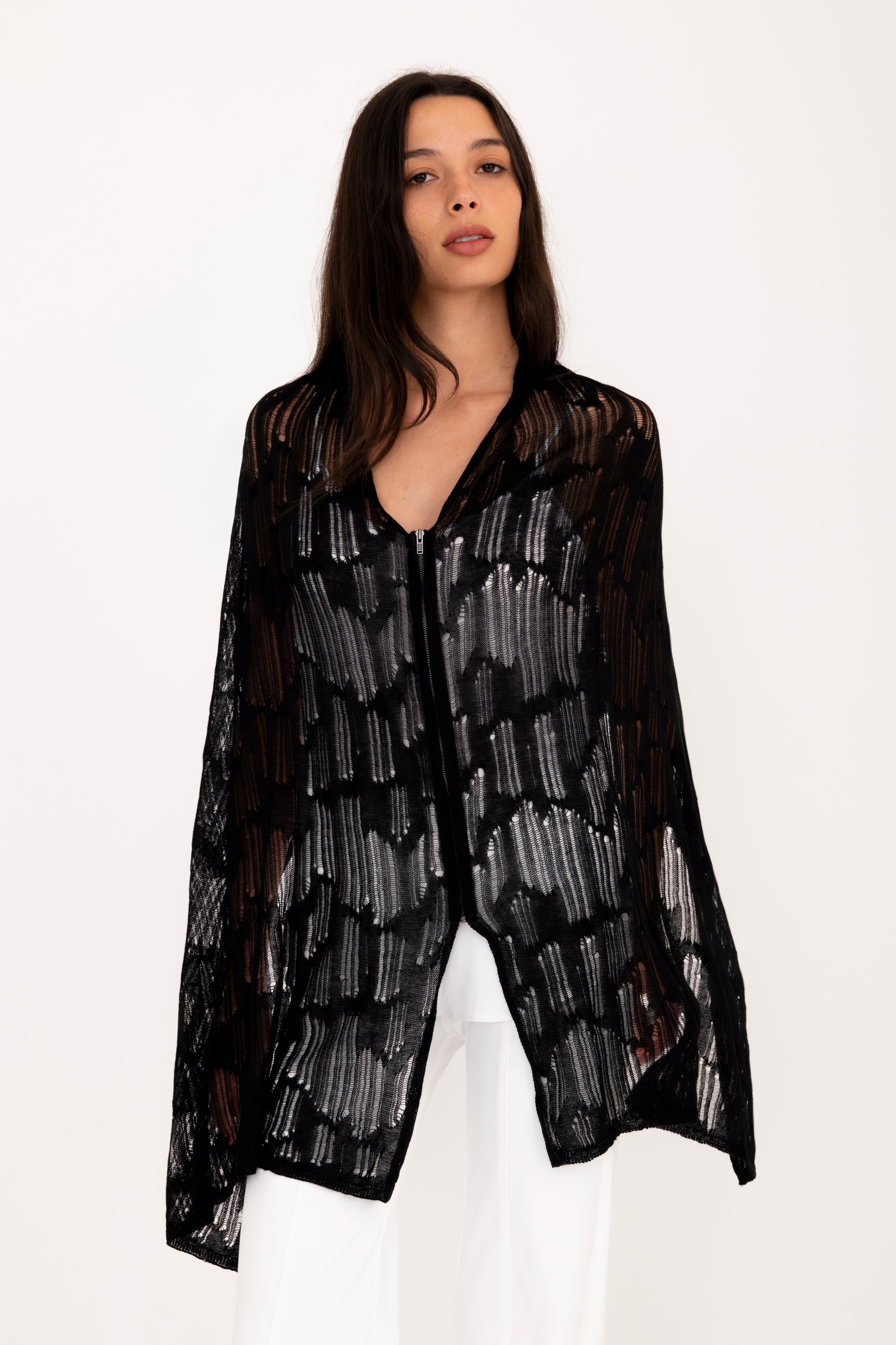Woman wearing a black poncho top on a white background
