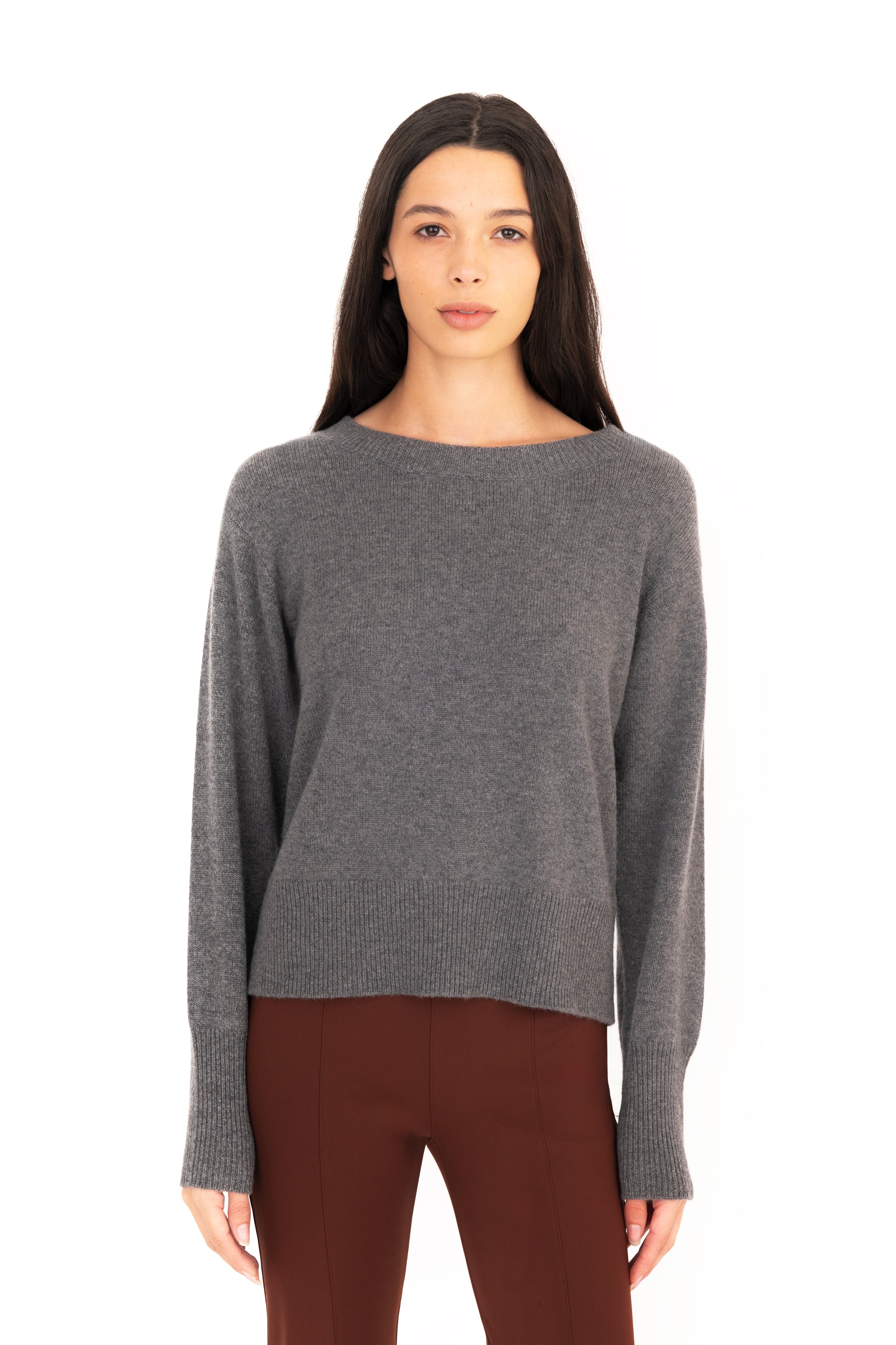 Woman wearing a gray sweater and brown pants on a white background