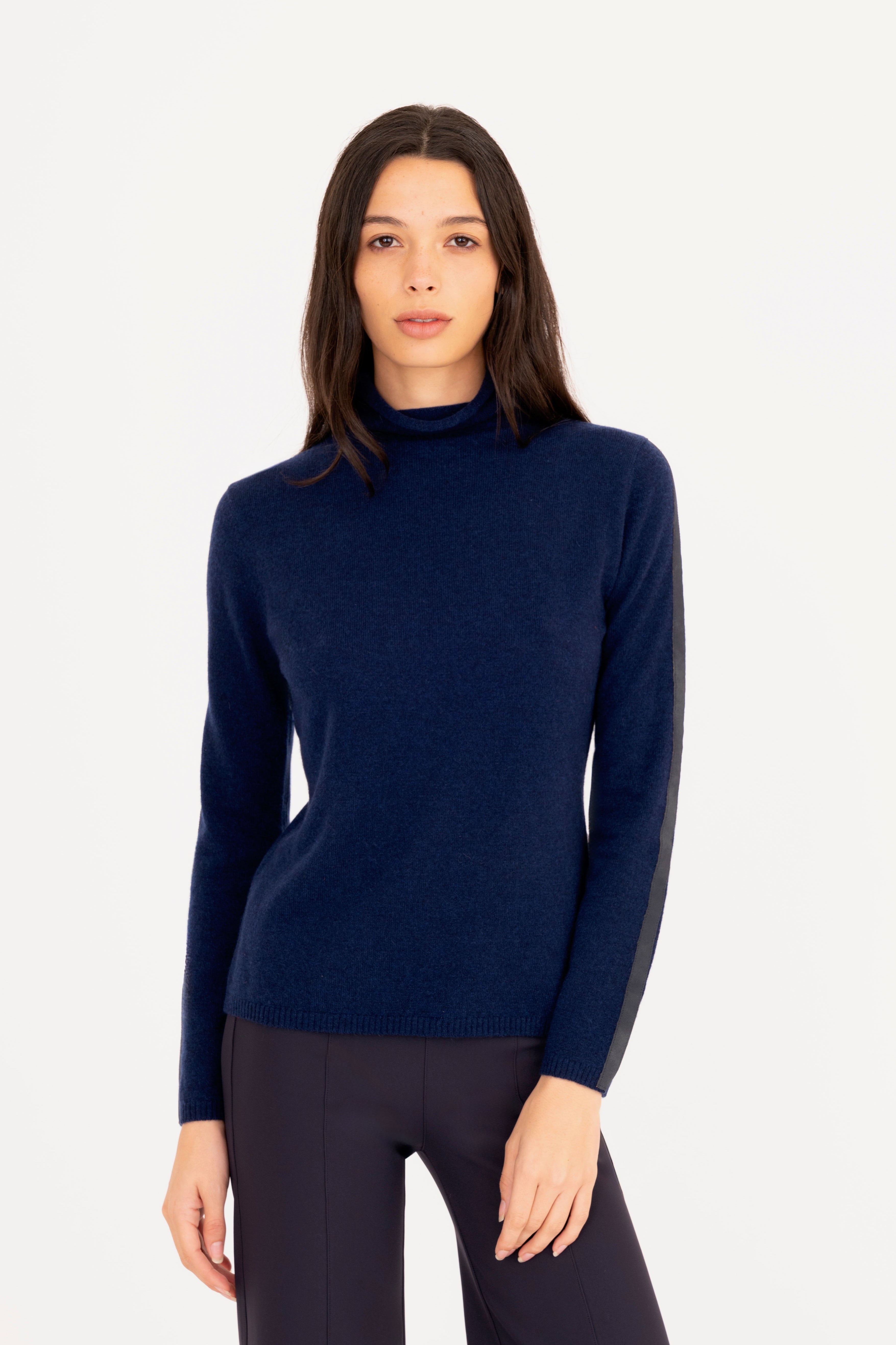Woman wearing a navy blue turtleneck sweater on a white background