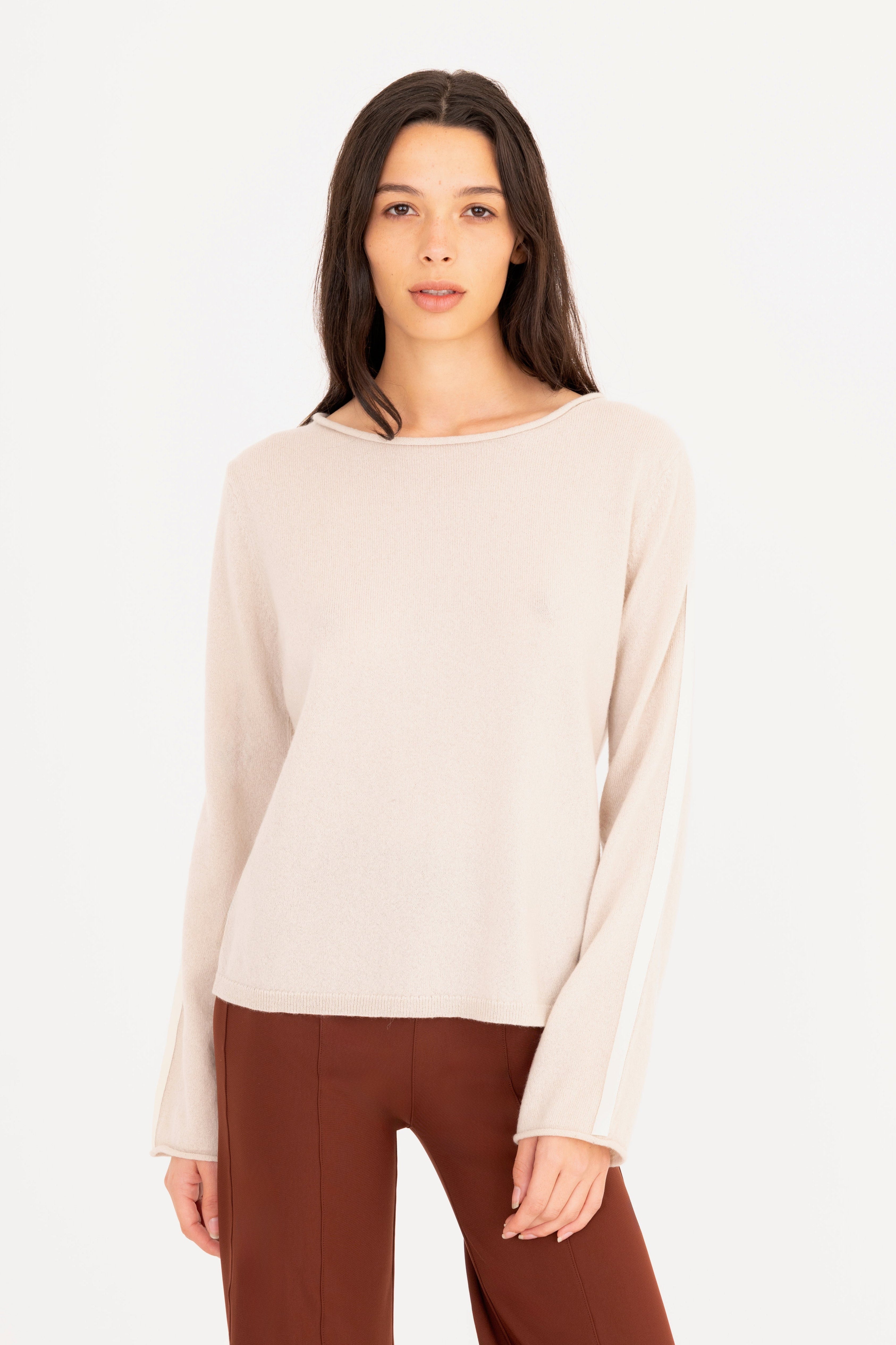 Woman wearing a beige long-sleeve top and brown pants on a white background