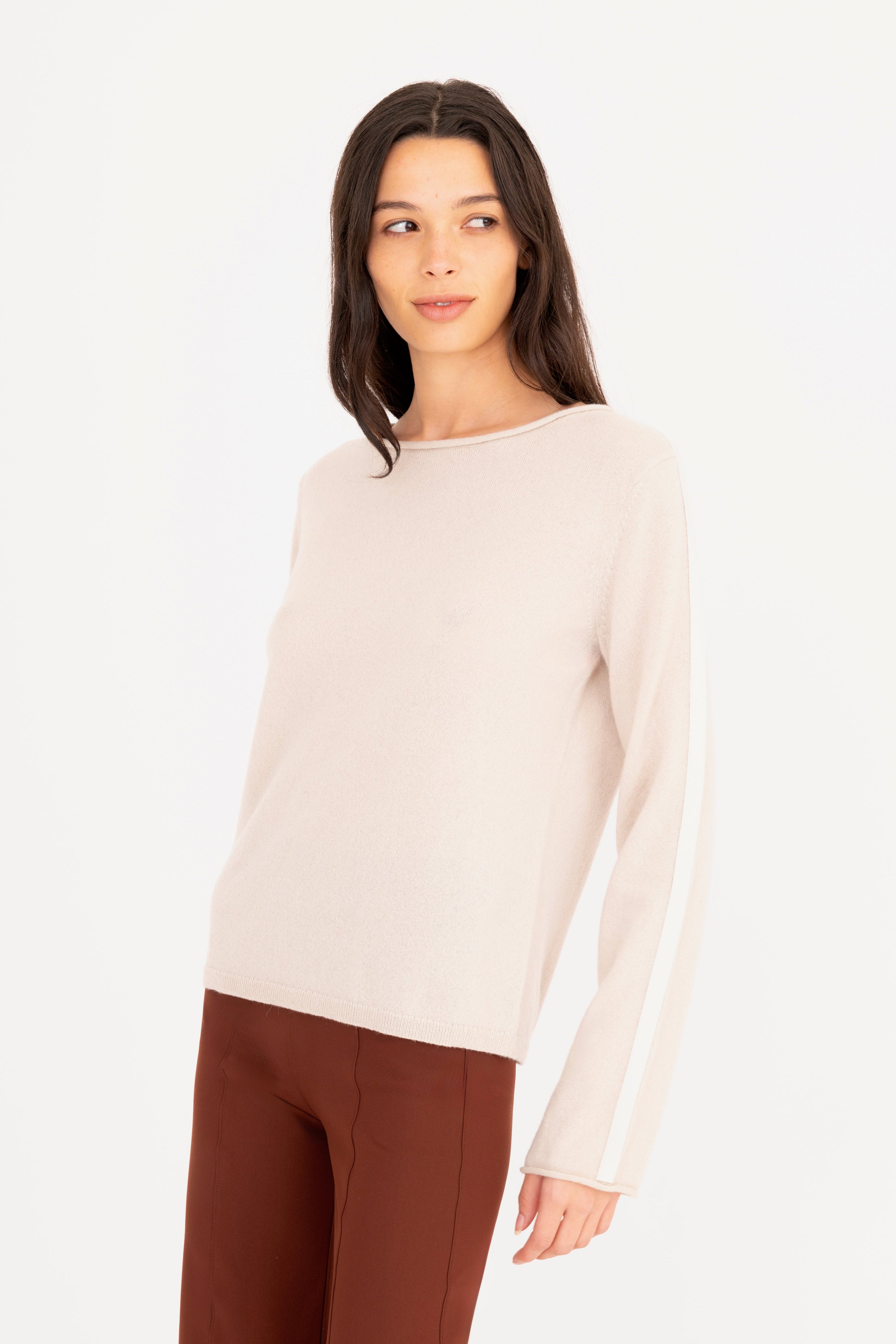 Woman wearing a beige sweater and brown pants on a white background