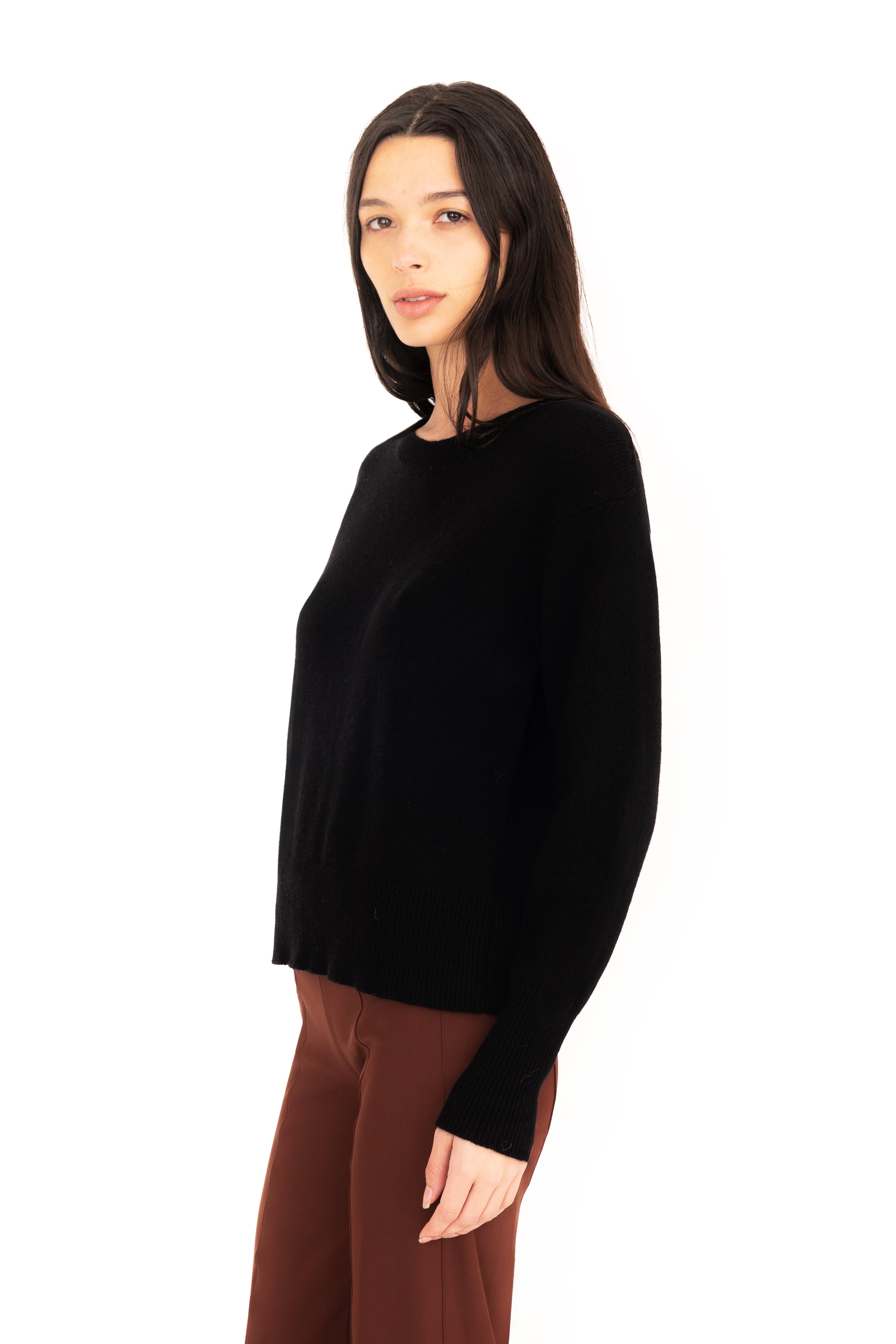 Woman wearing a black sweater and brown pants on a white background