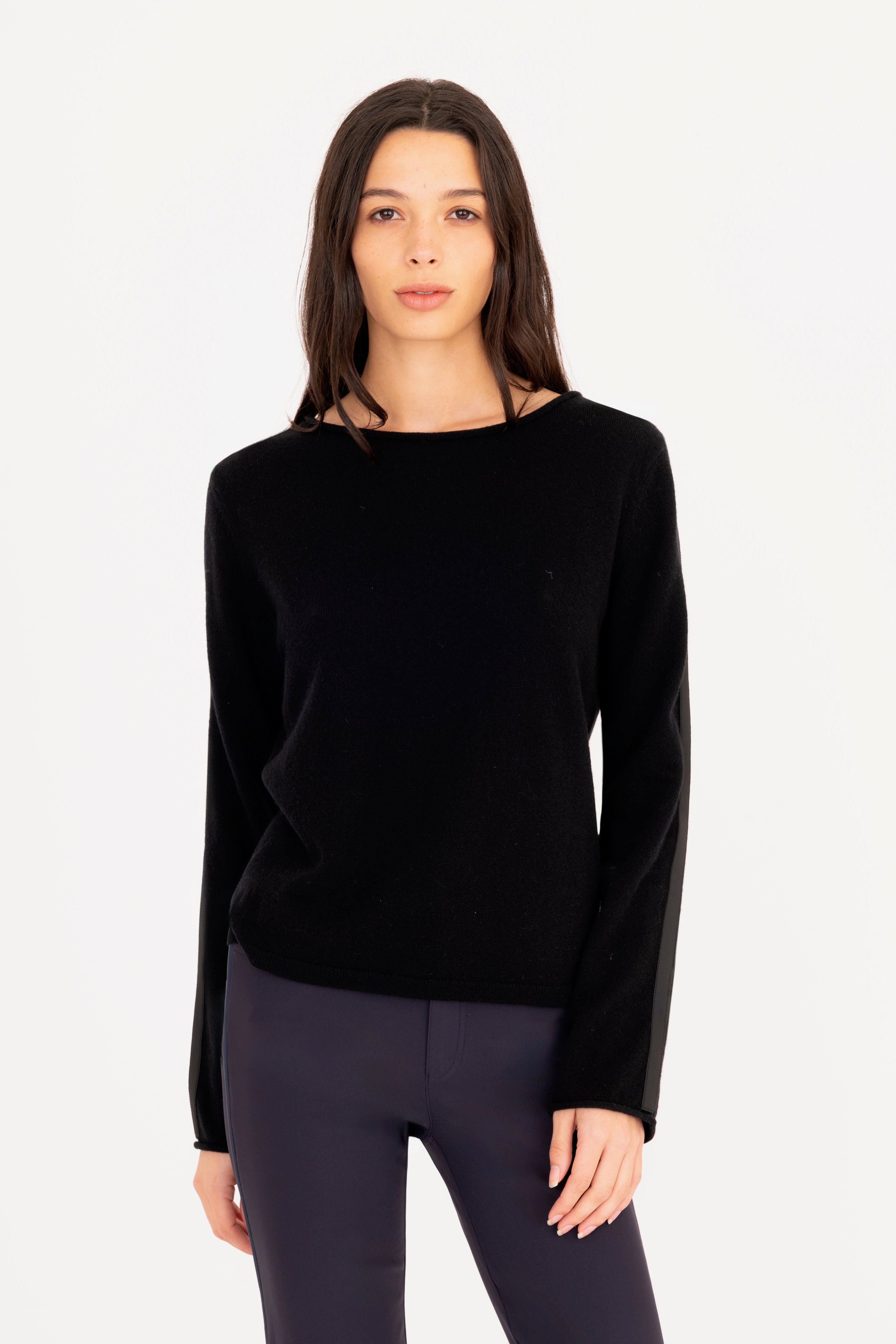 Woman wearing a black sweater and dark pants on a white background