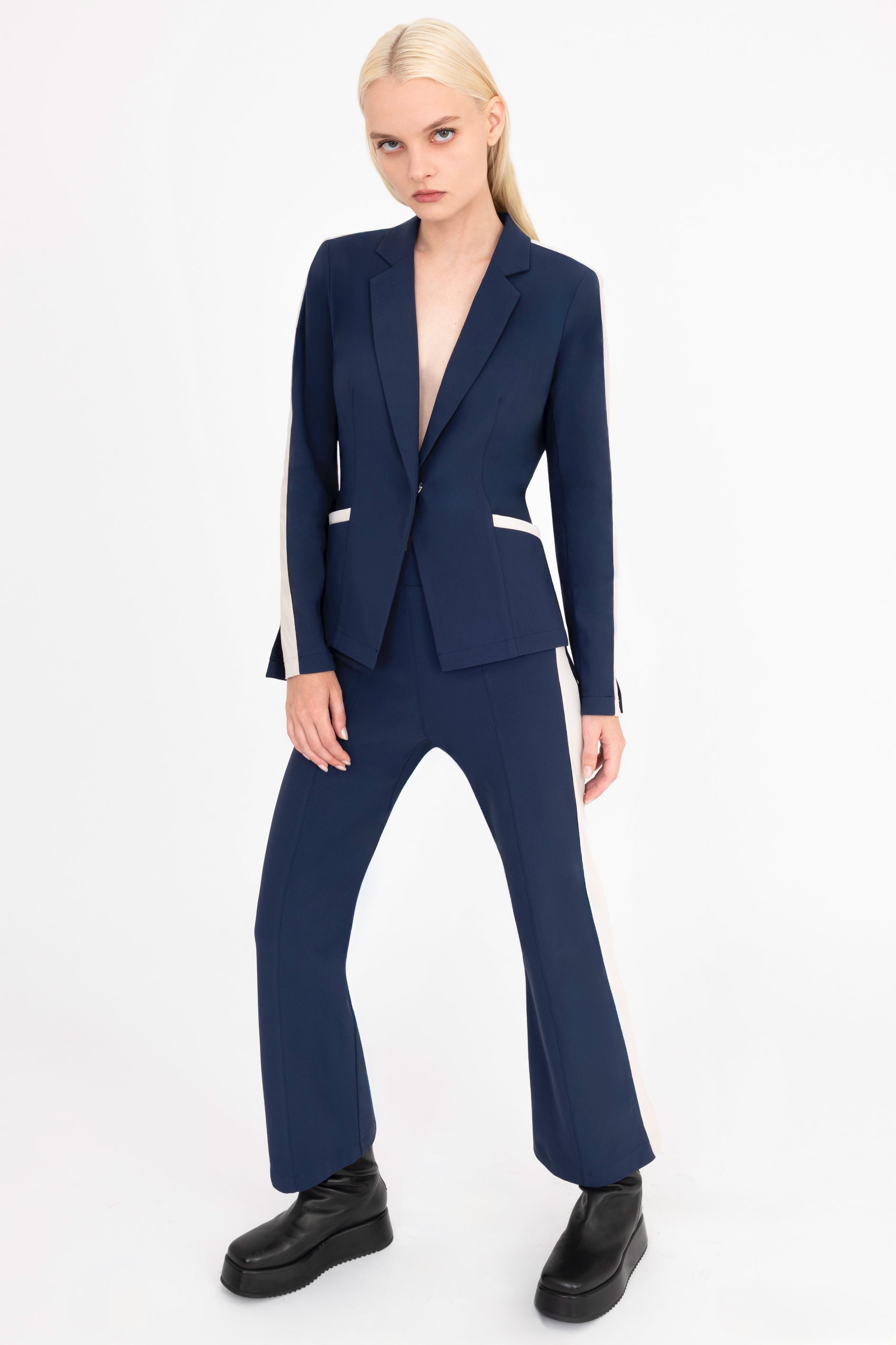 Woman wearing a indigo blue suit with beige side stripe on a white background