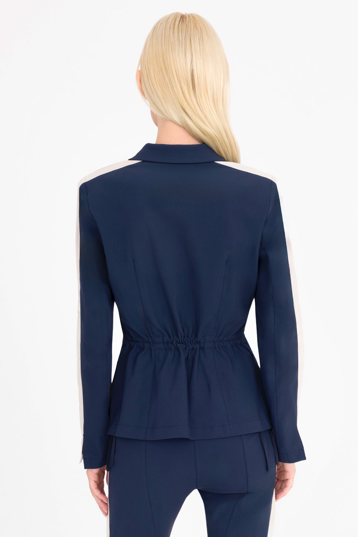 Woman wearing a indigo blue suit with beige side stripe on a white background