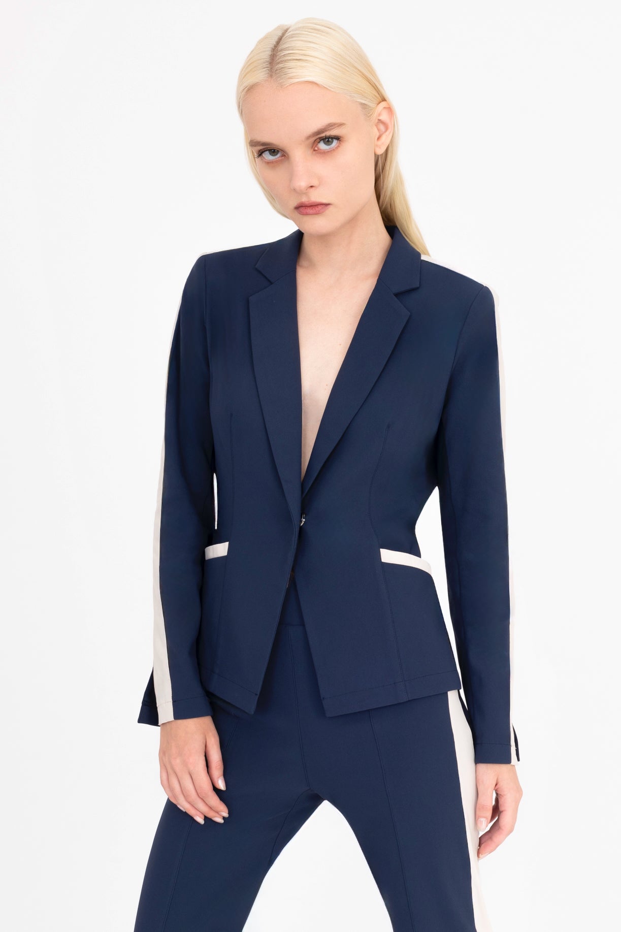 Woman wearing a indigo blue suit with beige side stripe on a white background