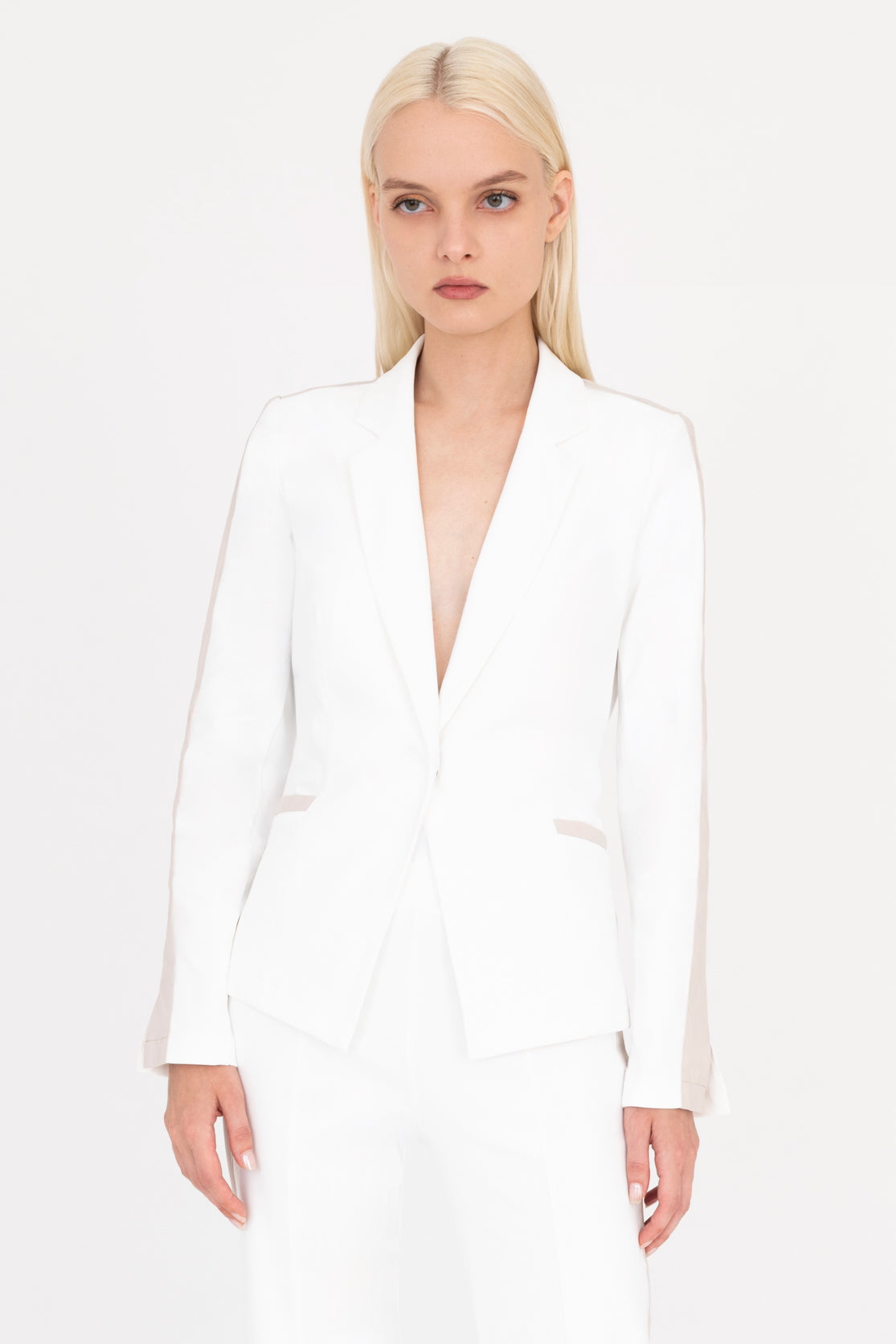 Woman wearing a white blazer with beige side stripe on a white background