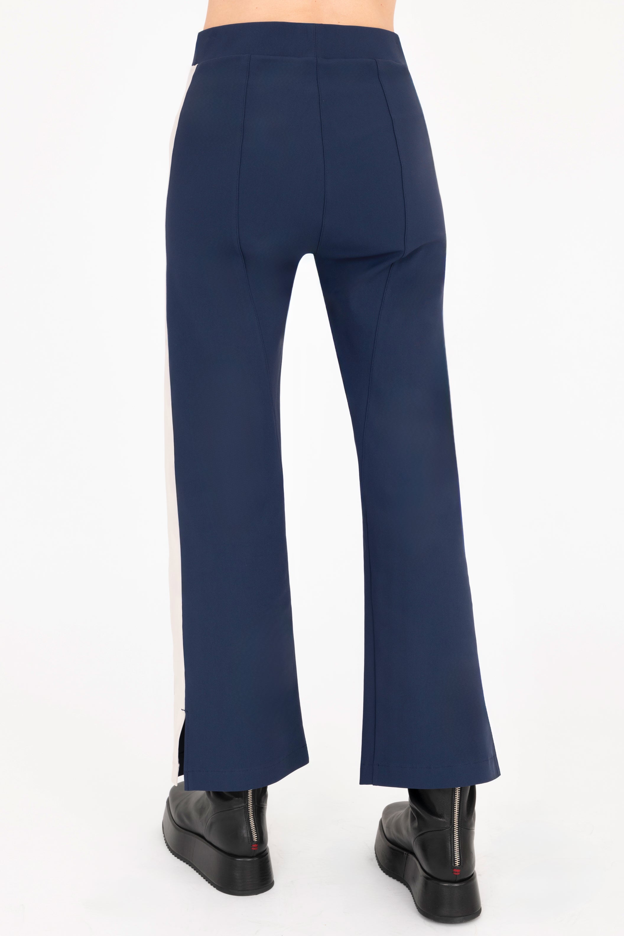 Back view of indigo blue cropped pants with beige side stripe on a white background