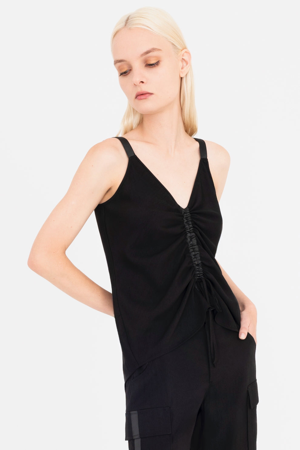 Woman wearing a black sleeveless top with a ruched design on a white background