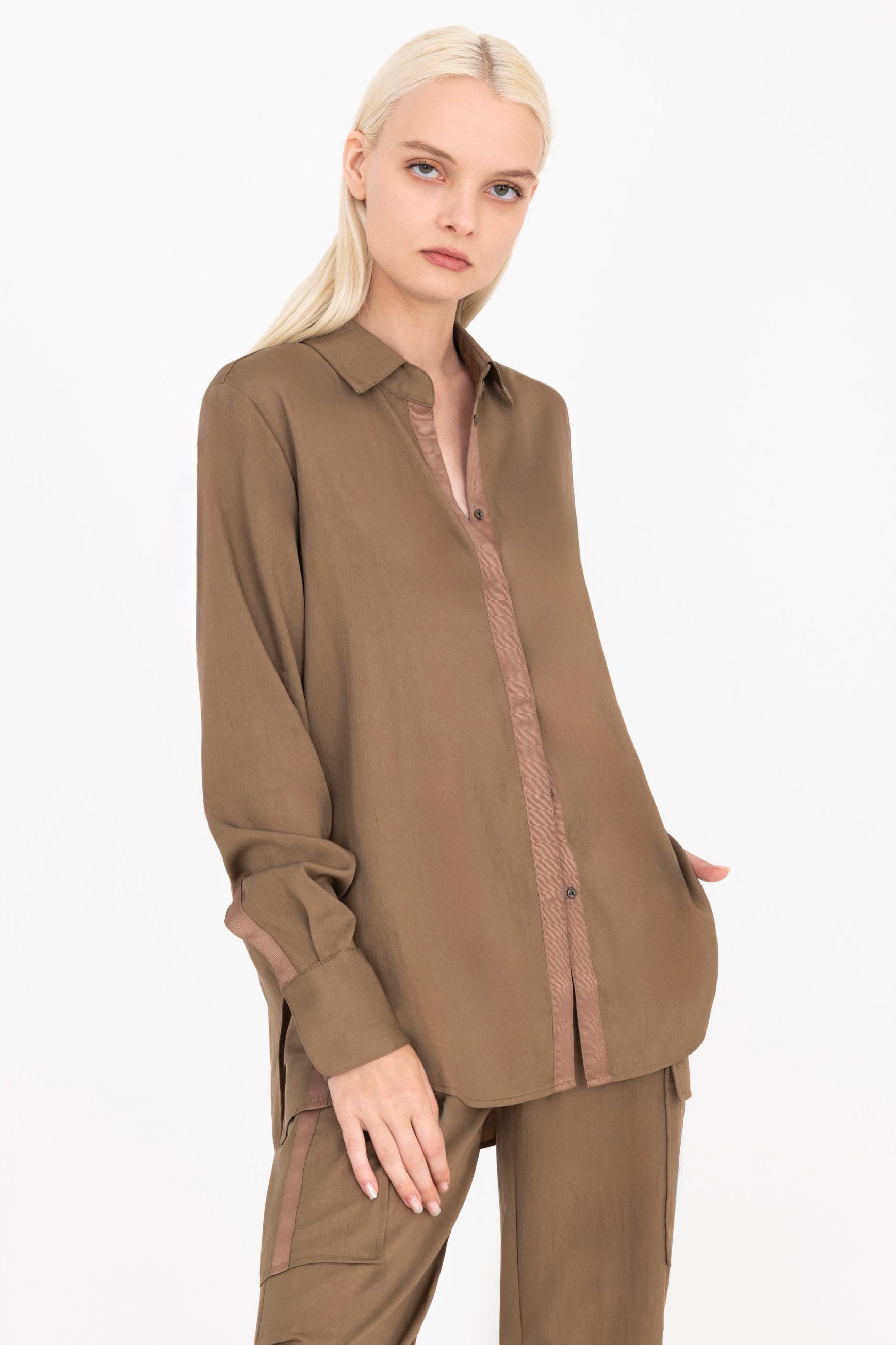 Quarter view of woman wearing a brown shirt and pants on a white background