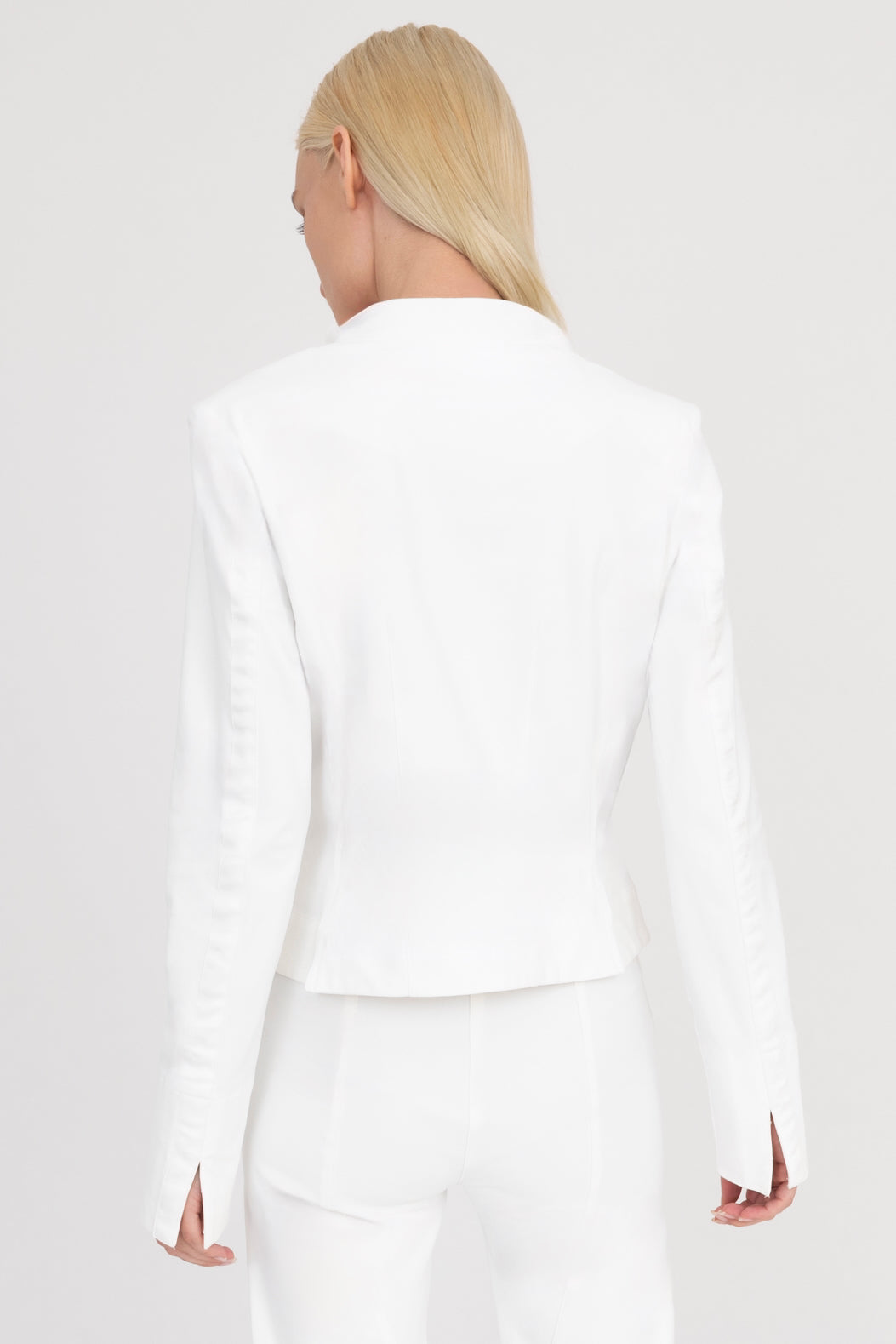 Woman wearing a white moto jacket and pants on a white background