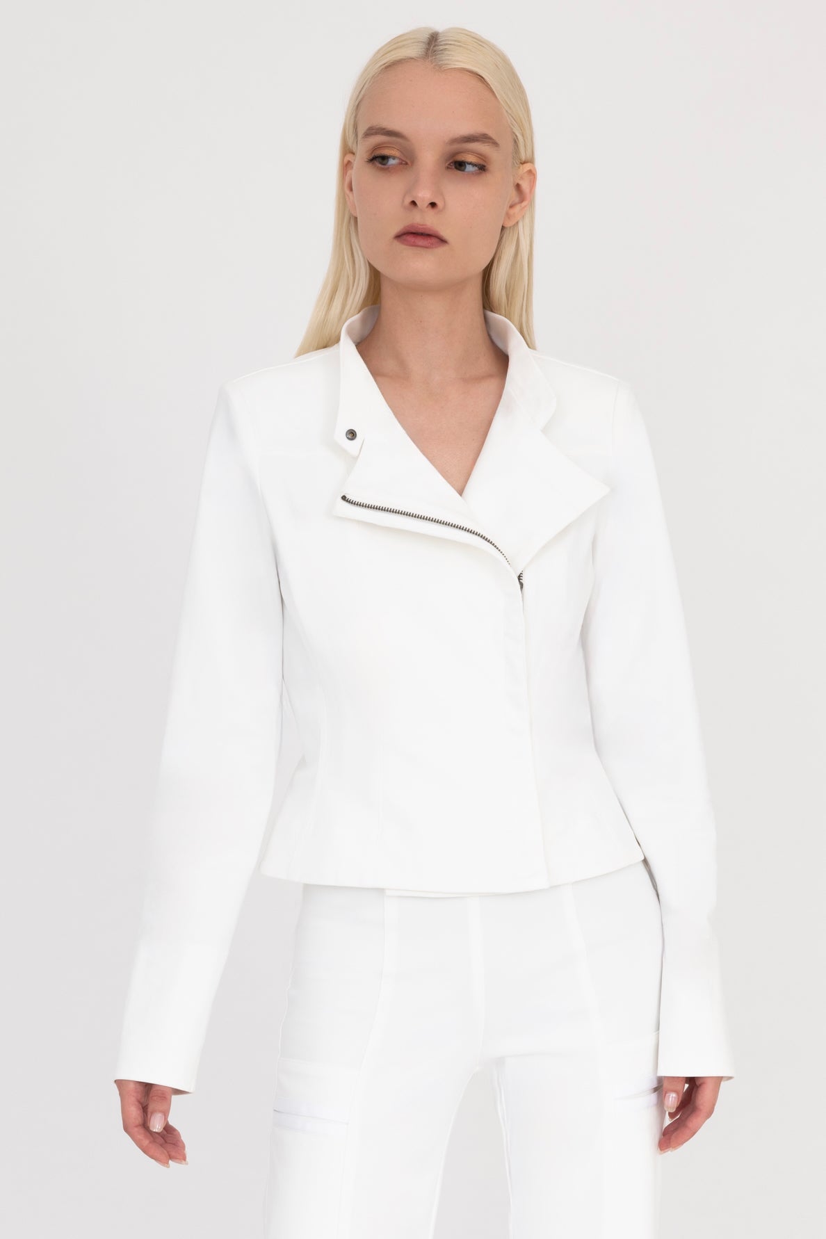 Woman wearing a white moto jacket and pants on a white background