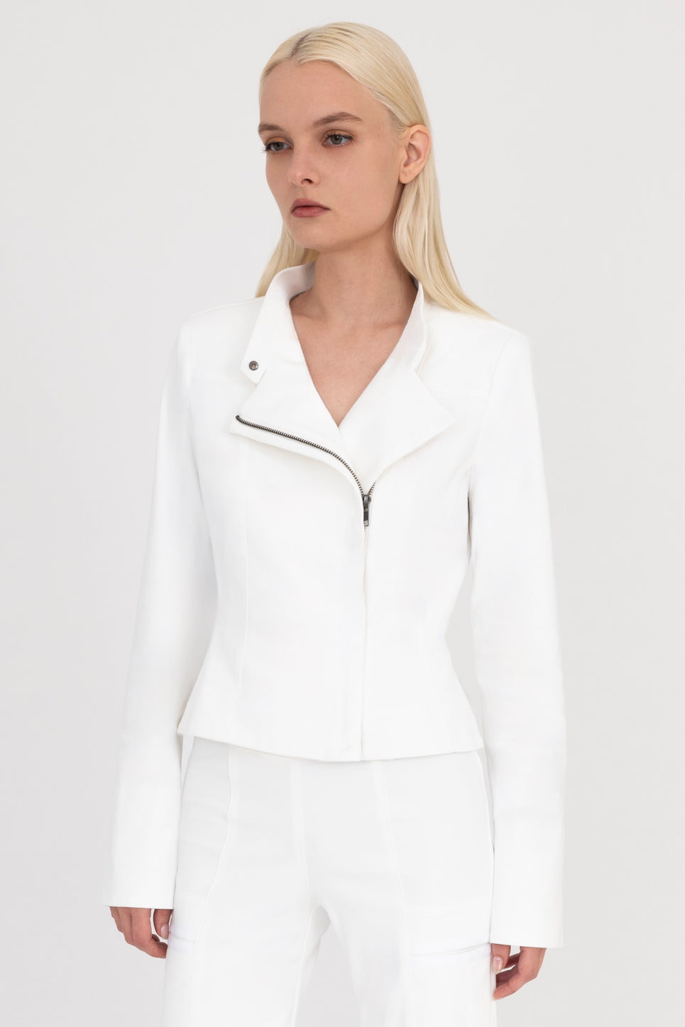 Woman wearing a white moto jacket and pants on a white background