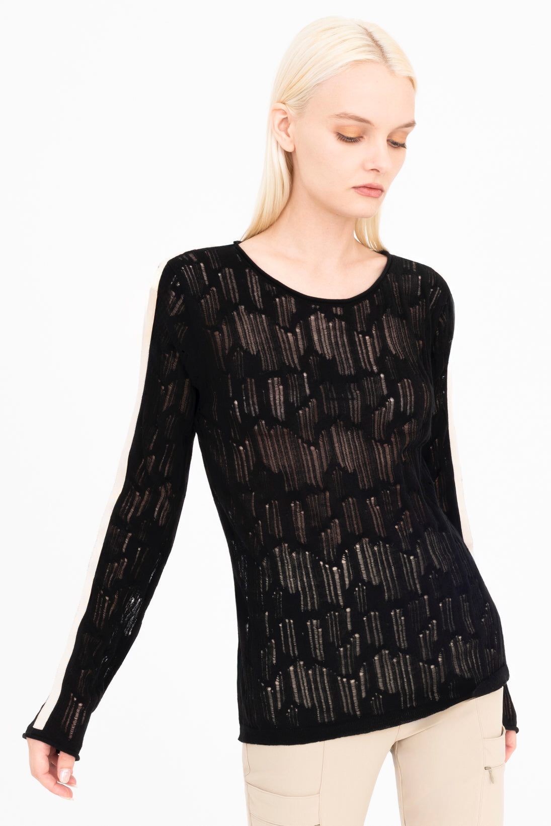 Woman wearing a black sheer long-sleeve top with white stripes on a white background