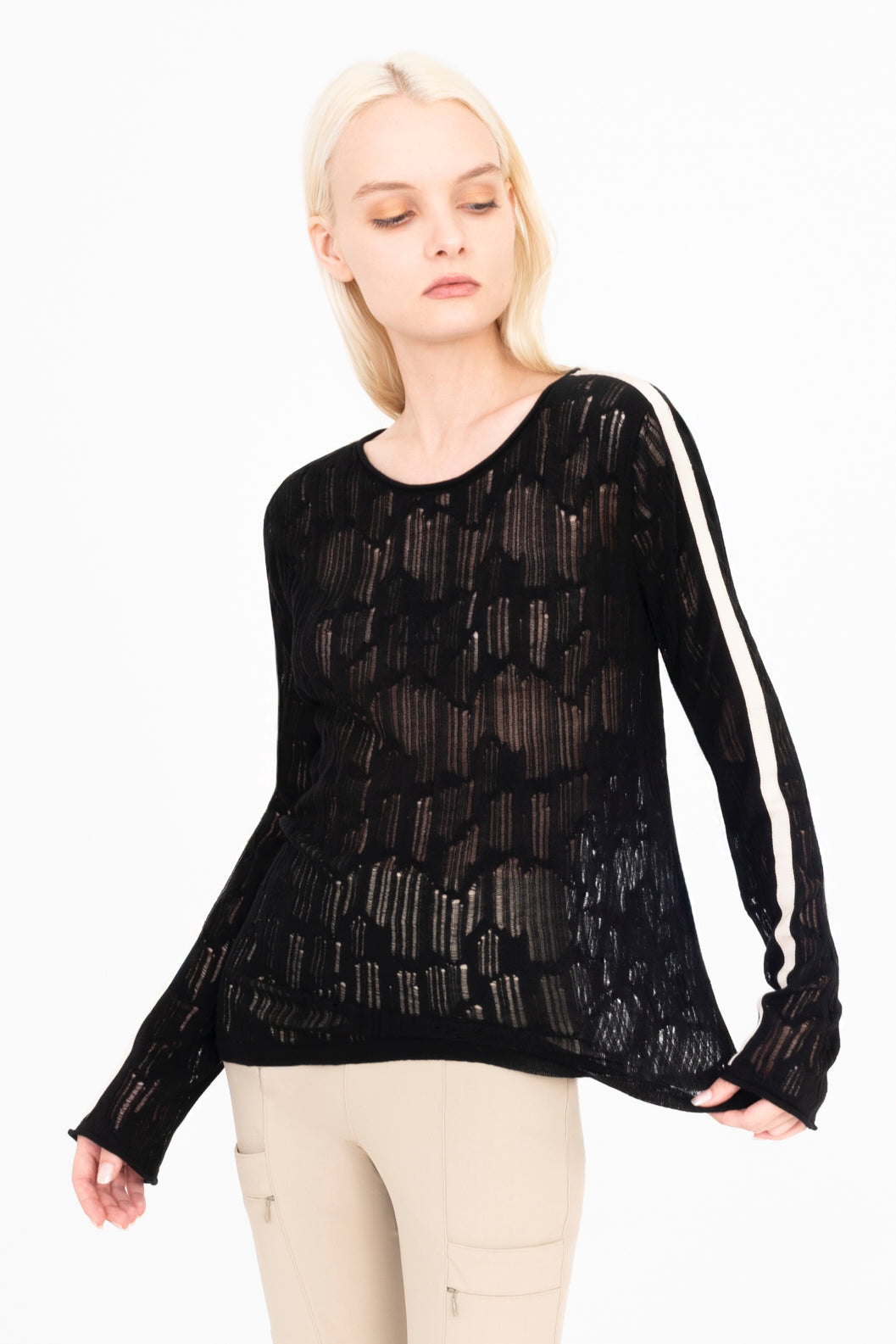 Woman wearing a black sheer long-sleeve top with white stripes on a white background