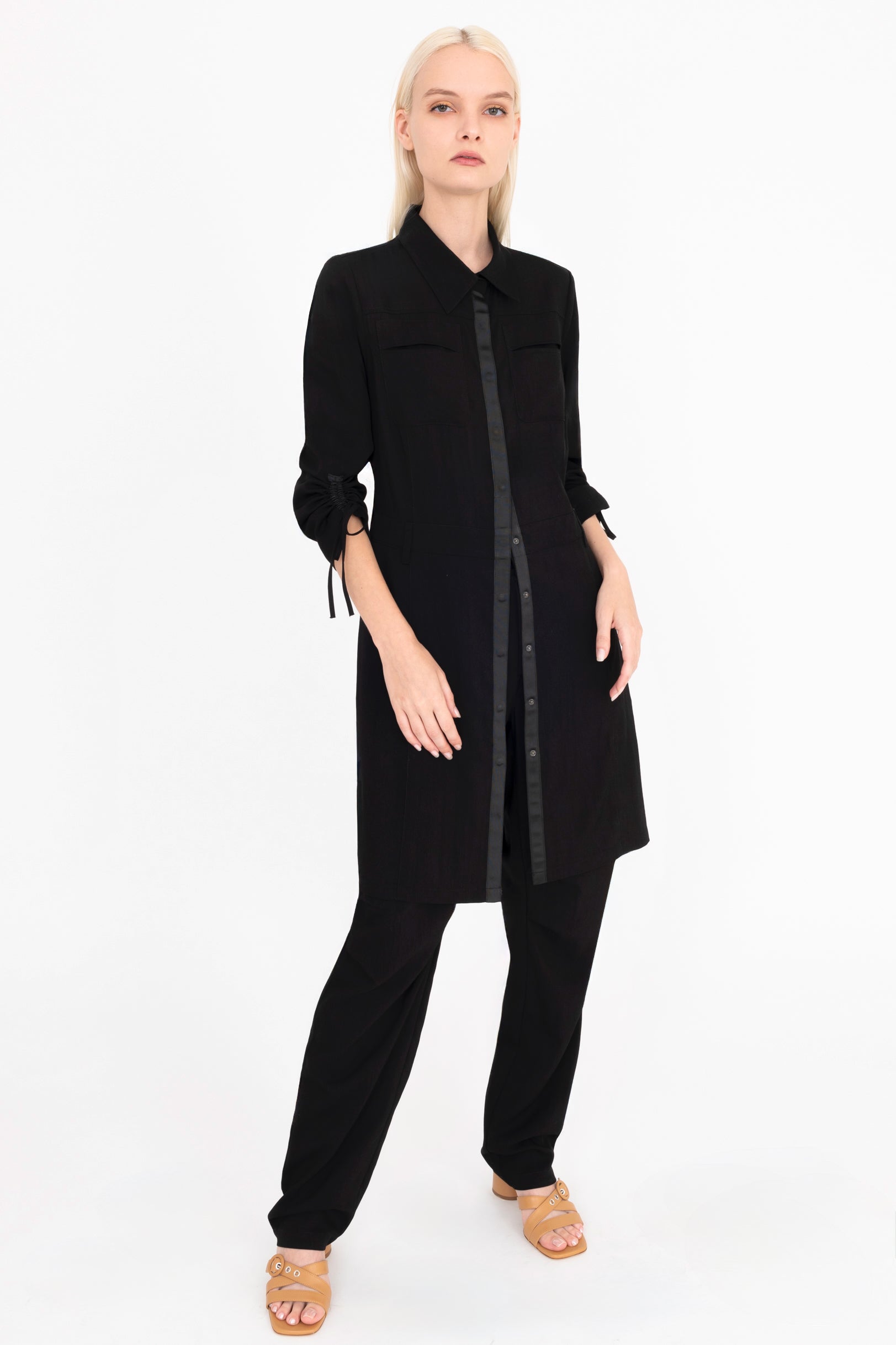 Front view of woman wearing a black dress and pants on a white background