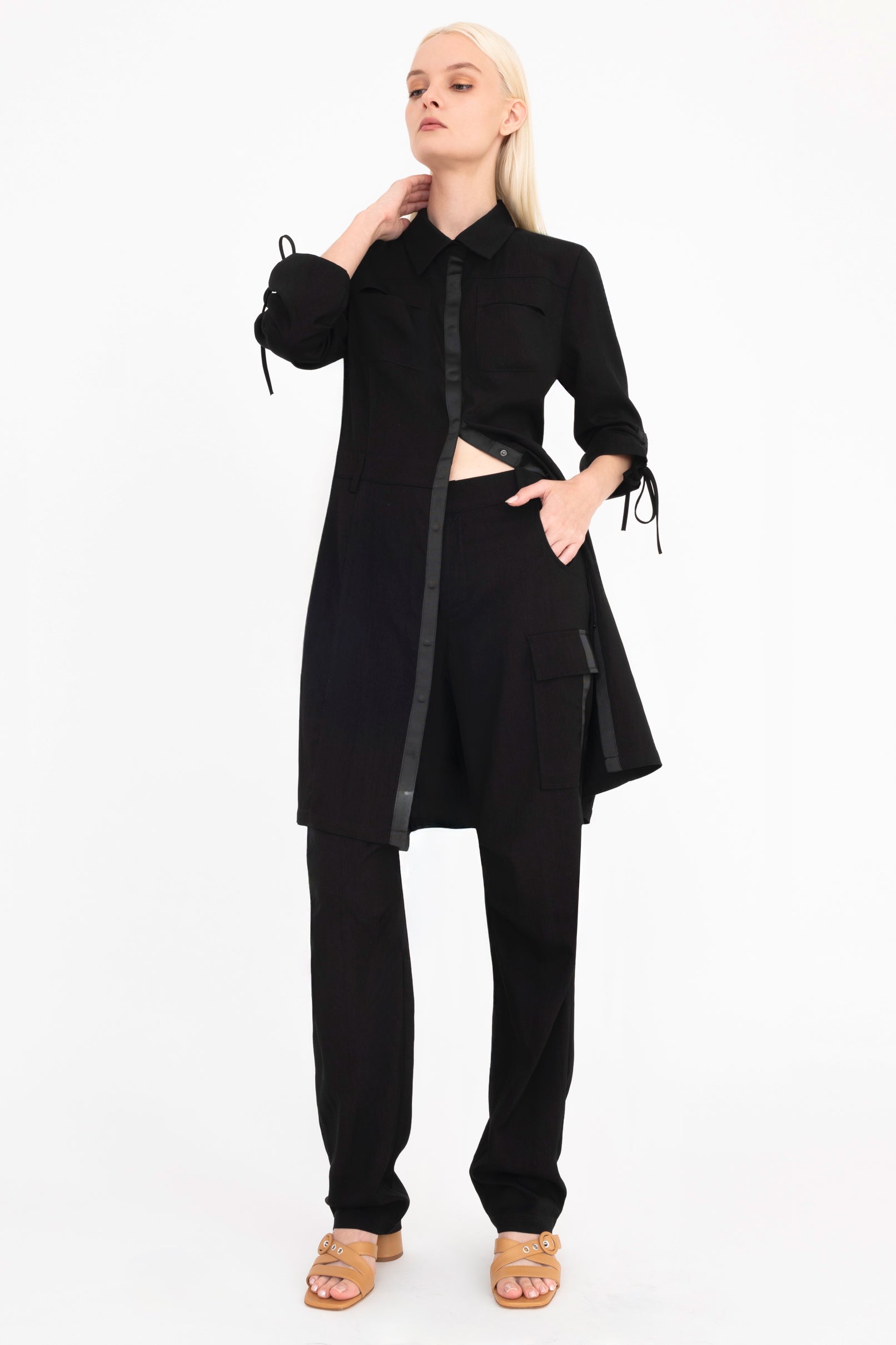 Quarter view of woman wearing a black dress and pants on a white background