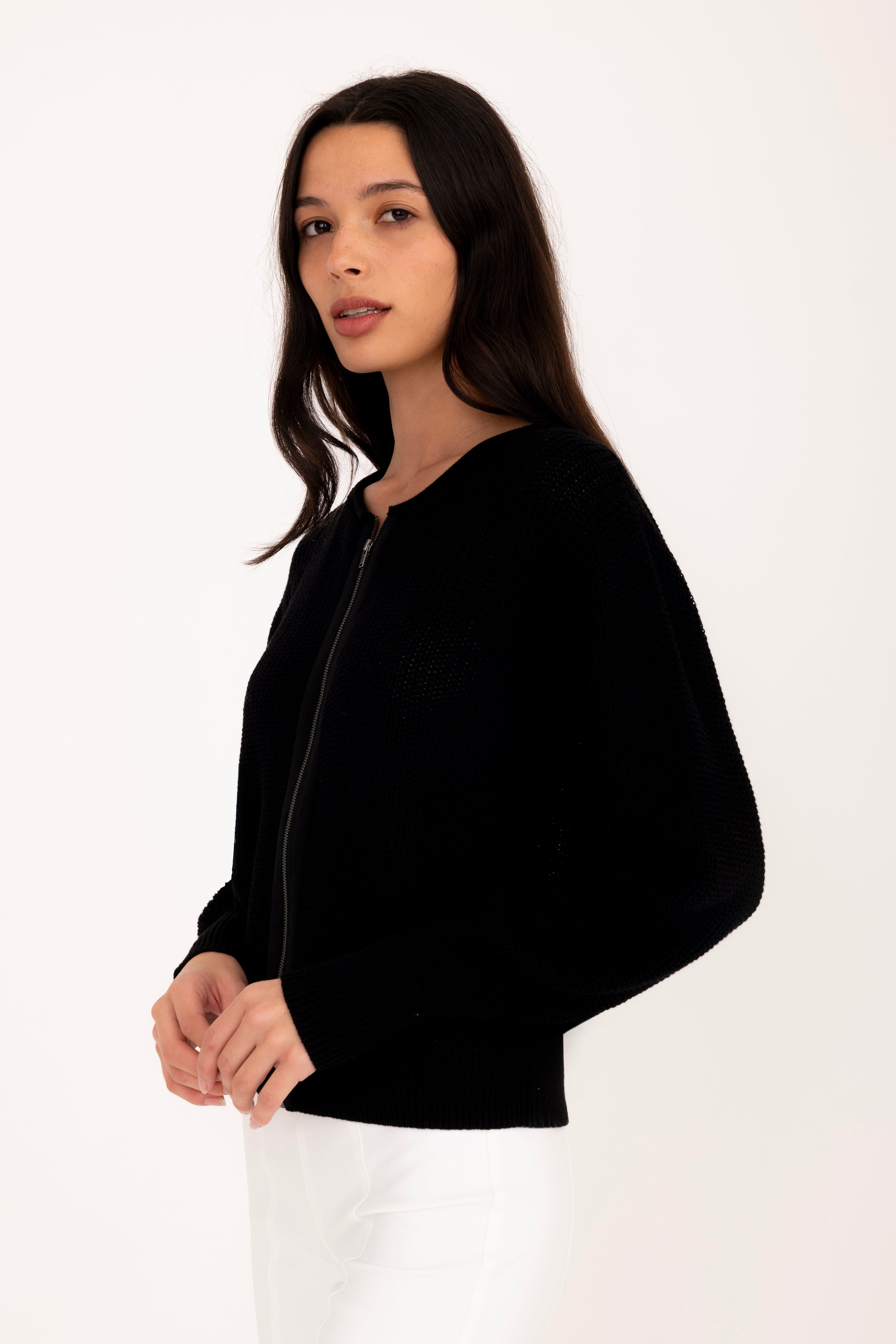 Woman wearing a black jacket over a white shirt on a white background