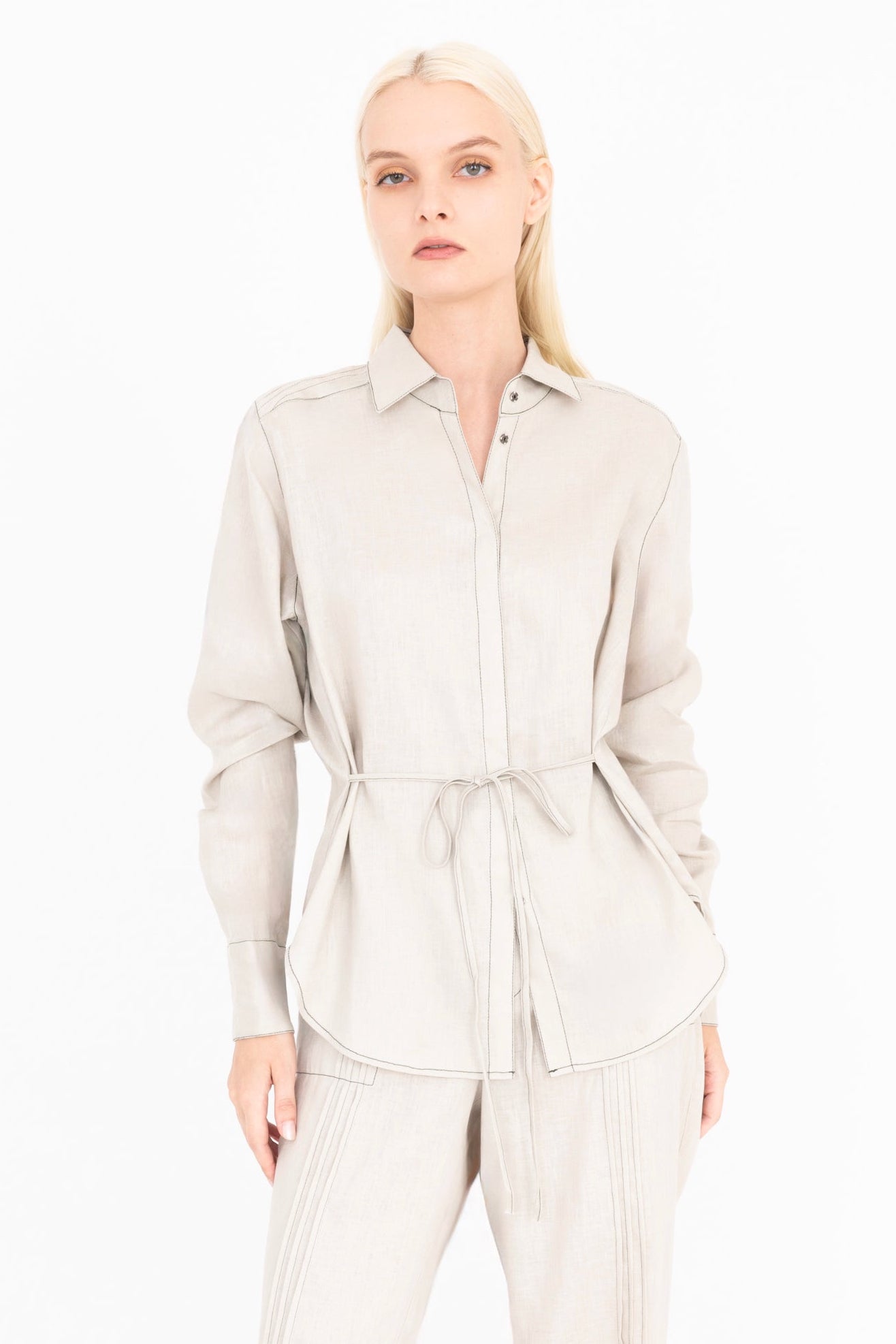 Woman wearing a beige shirt and pants on a white background