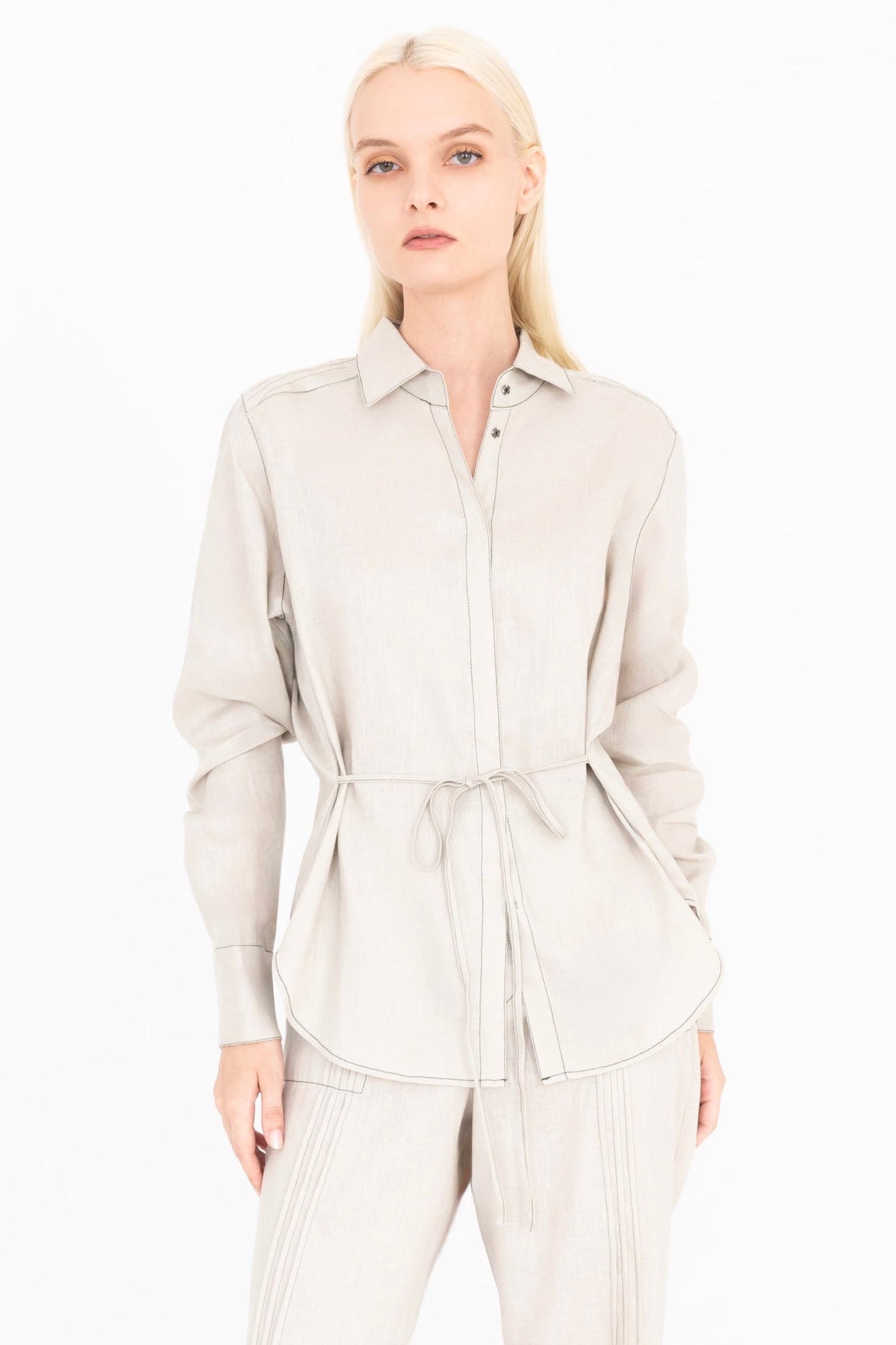 Woman wearing a beige shirt and pants on a white background