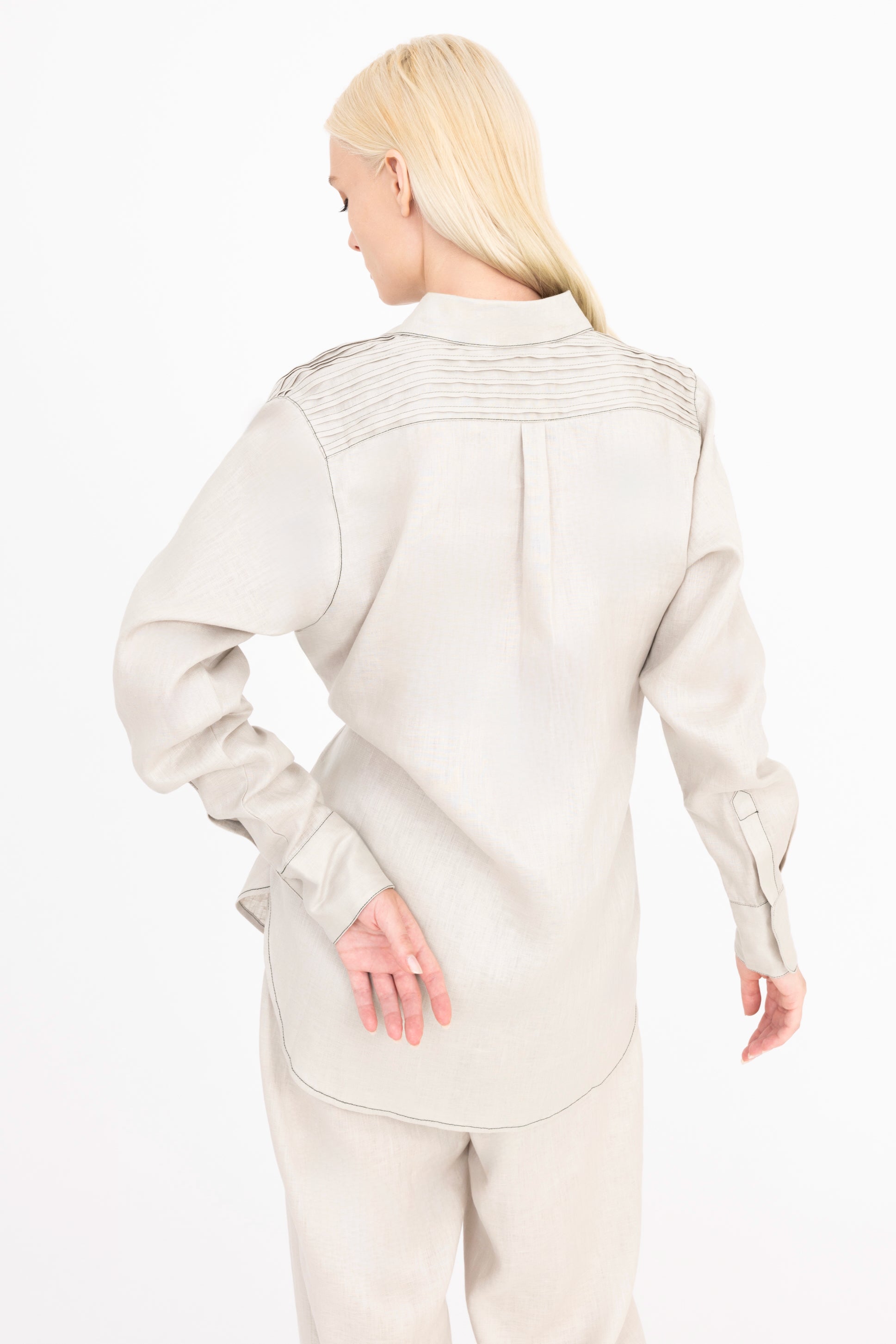 Woman wearing a beige shirt and pants on a white background