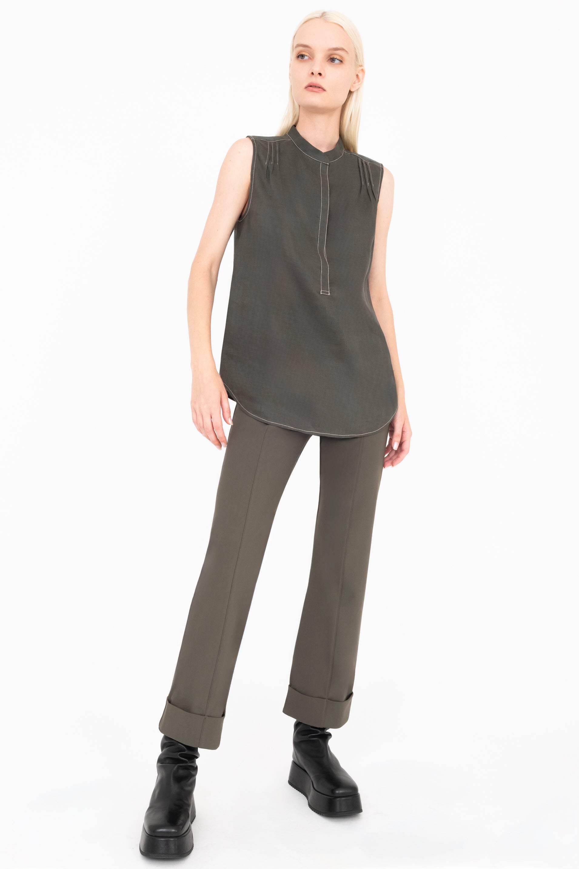 Woman wearing a sleeveless pine green top and matching pants on a white background