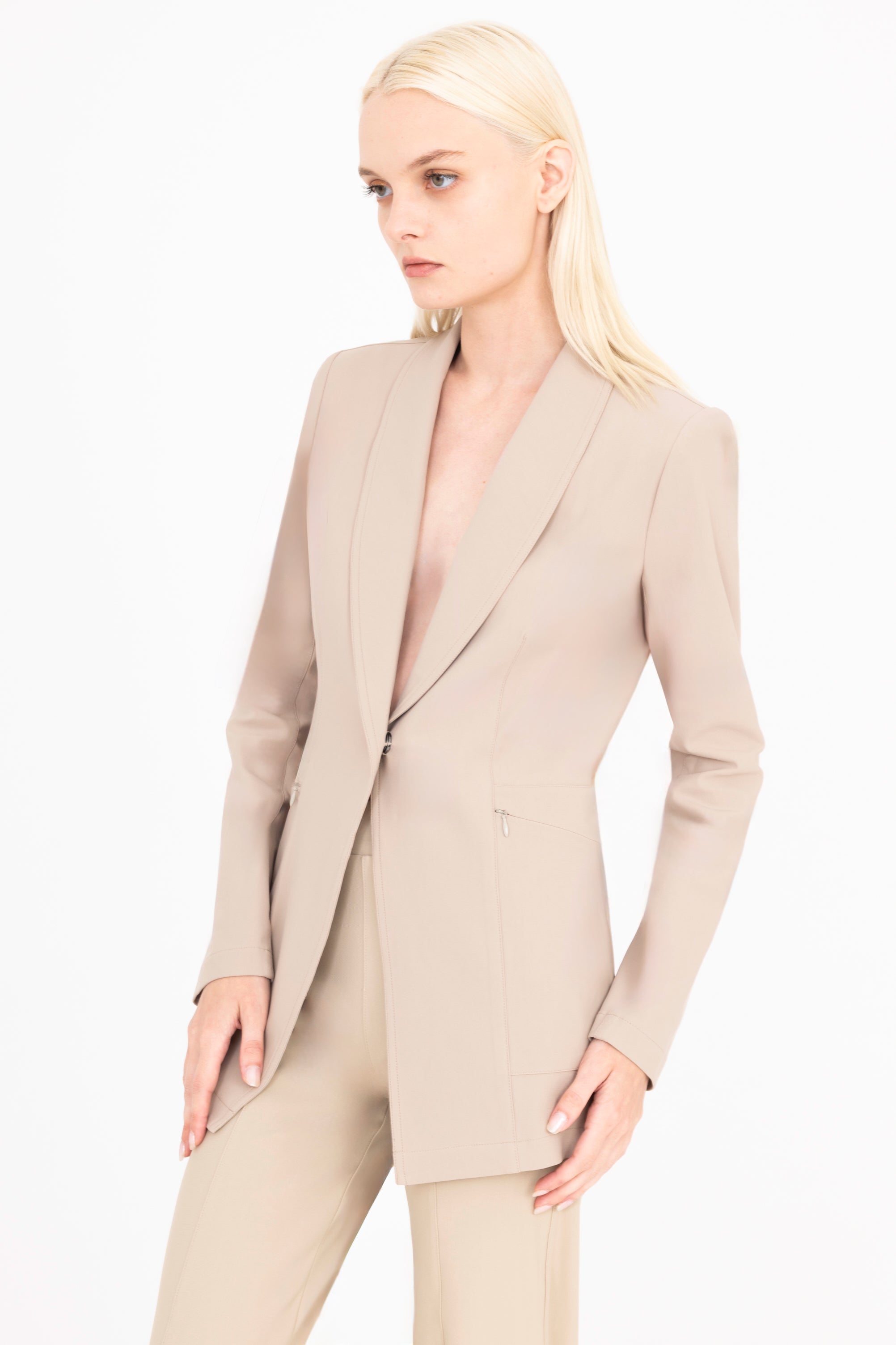 Woman wearing a beige blazer and pants on a white background