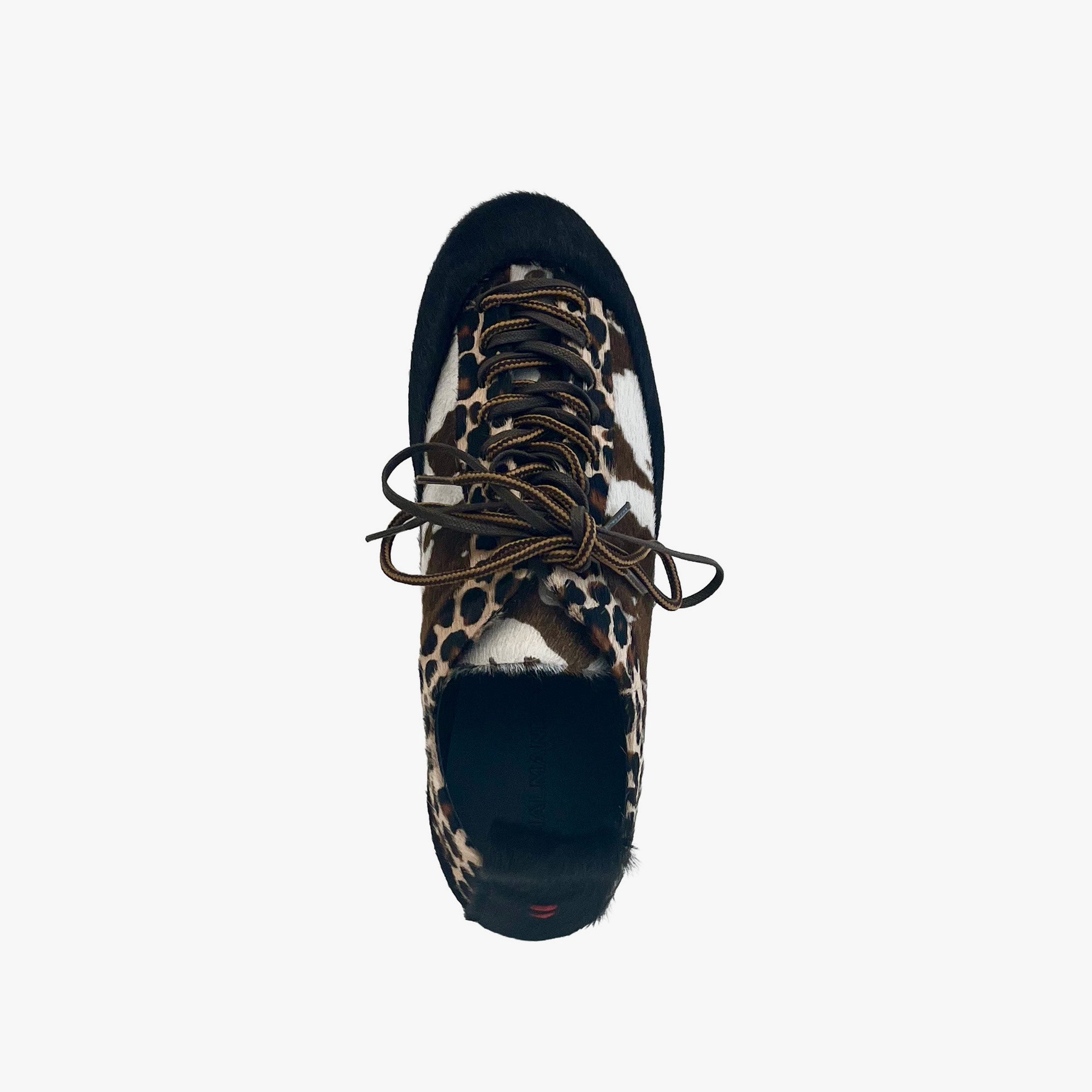 A single low-top sneaker shown from a top-down view on a light gray background. The shoe features a leopard print pattern on the side panels, a black suede-like toe cap and heel, white side panels, and dark brown laces.