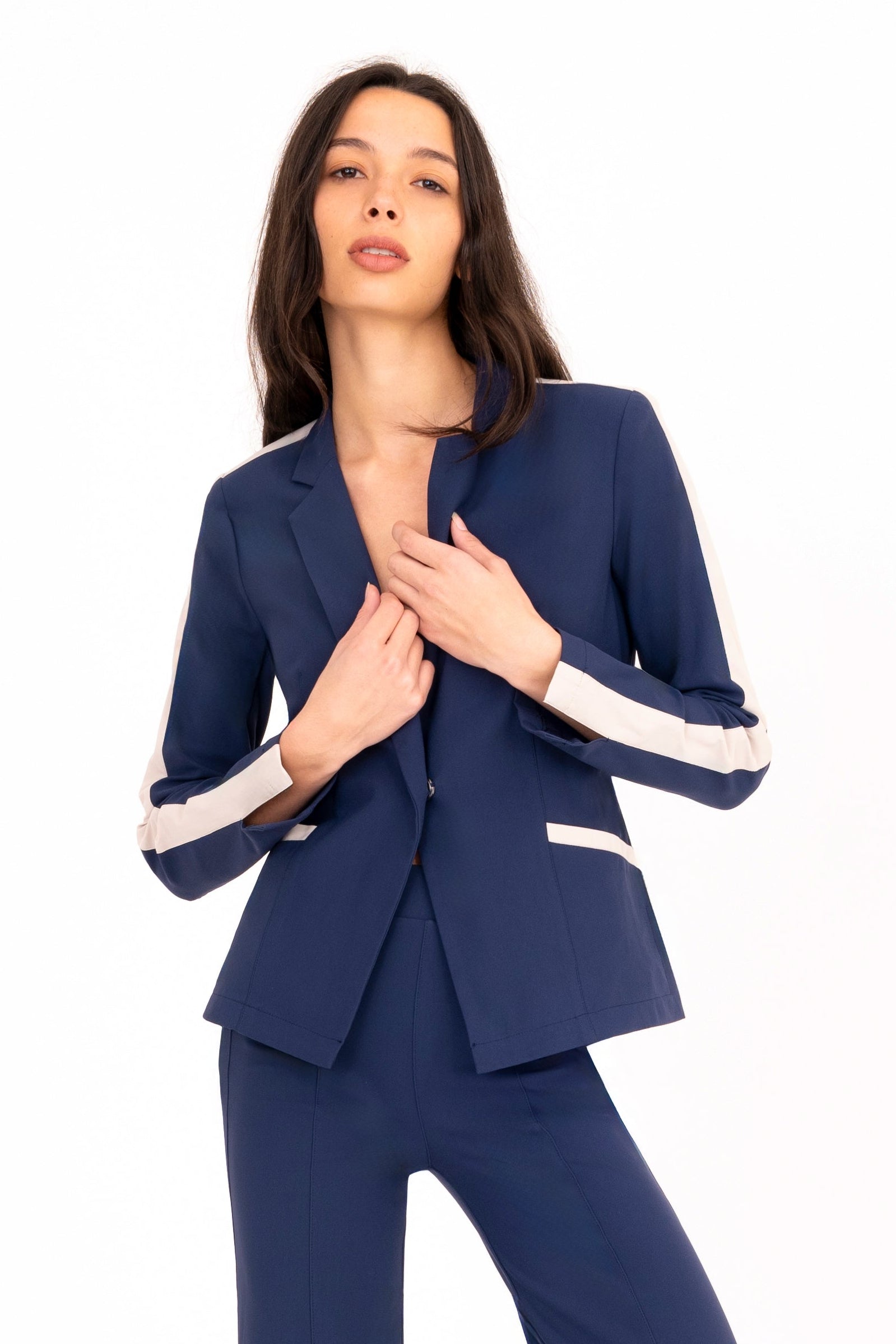 Woman wearing a navy blue suit with white accents on a white background