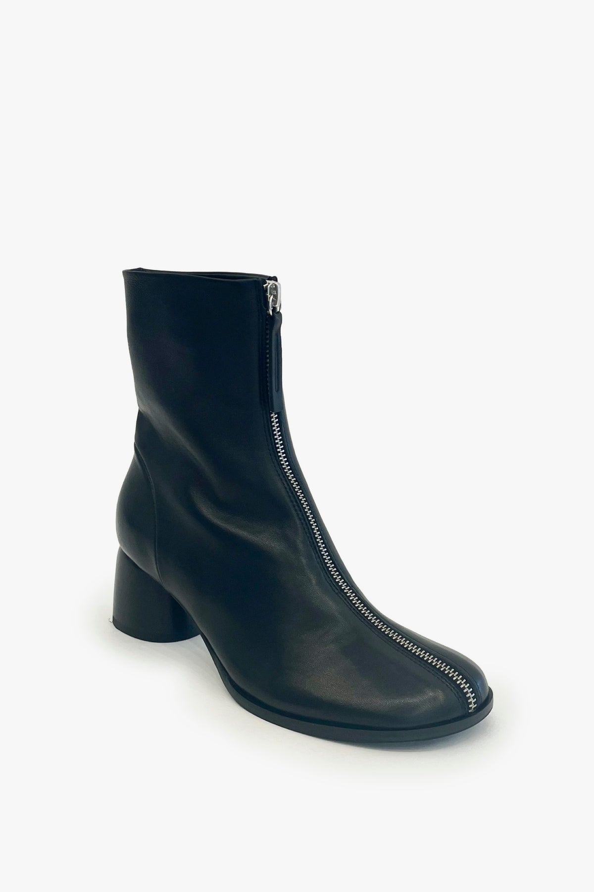 A black leather ankle boot with a low block heel and a silver zipper running down the front, shown on a clean white background.