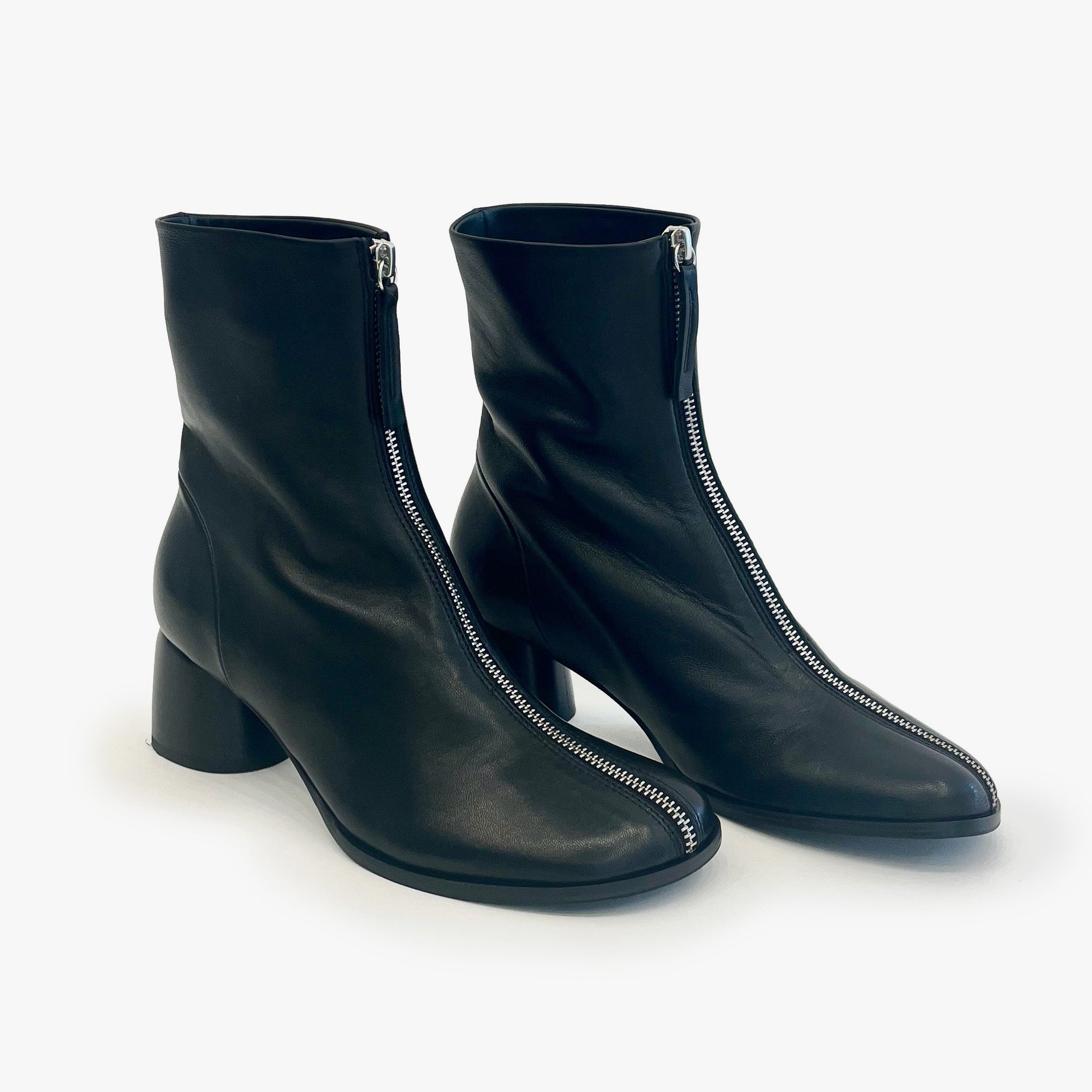 A pair of black leather ankle boots with a low block heel and a silver zipper running down the front, displayed on a clean white background.