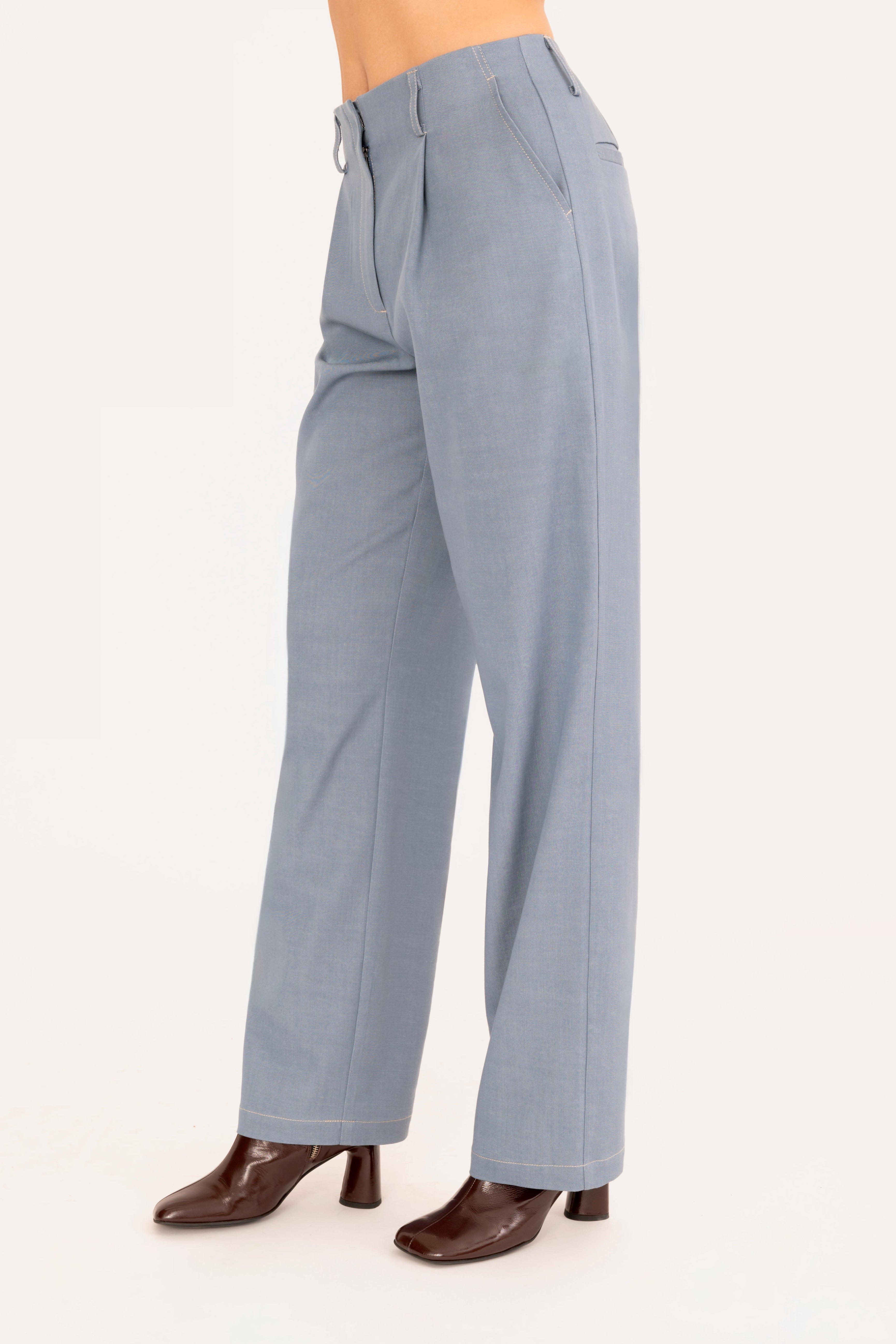 A model is shown from the waist down wearing a pair of light blue denim trousers and dark brown heeled boots against a plain off-white background.