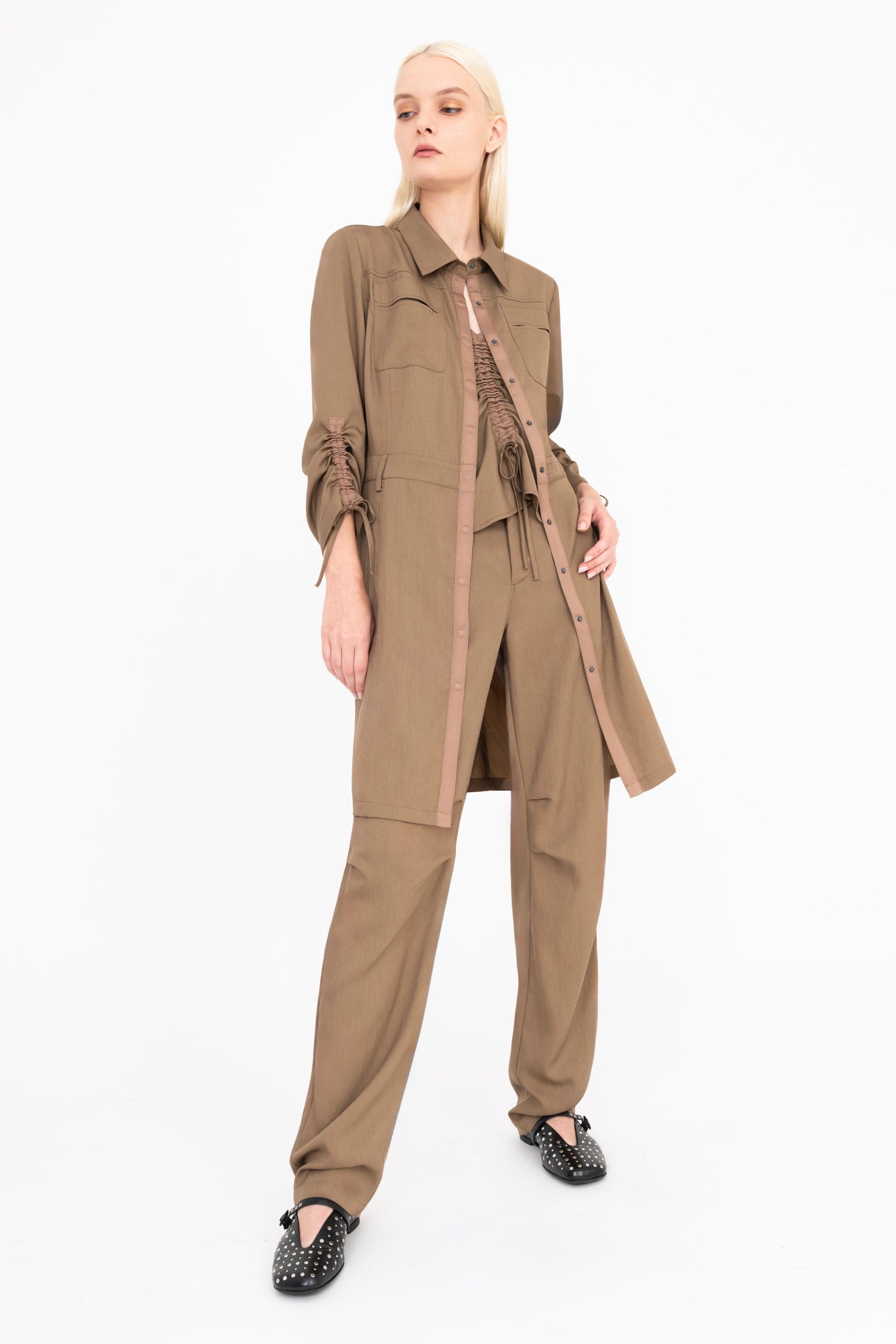 Woman wearing a beige coat and pants on a white background