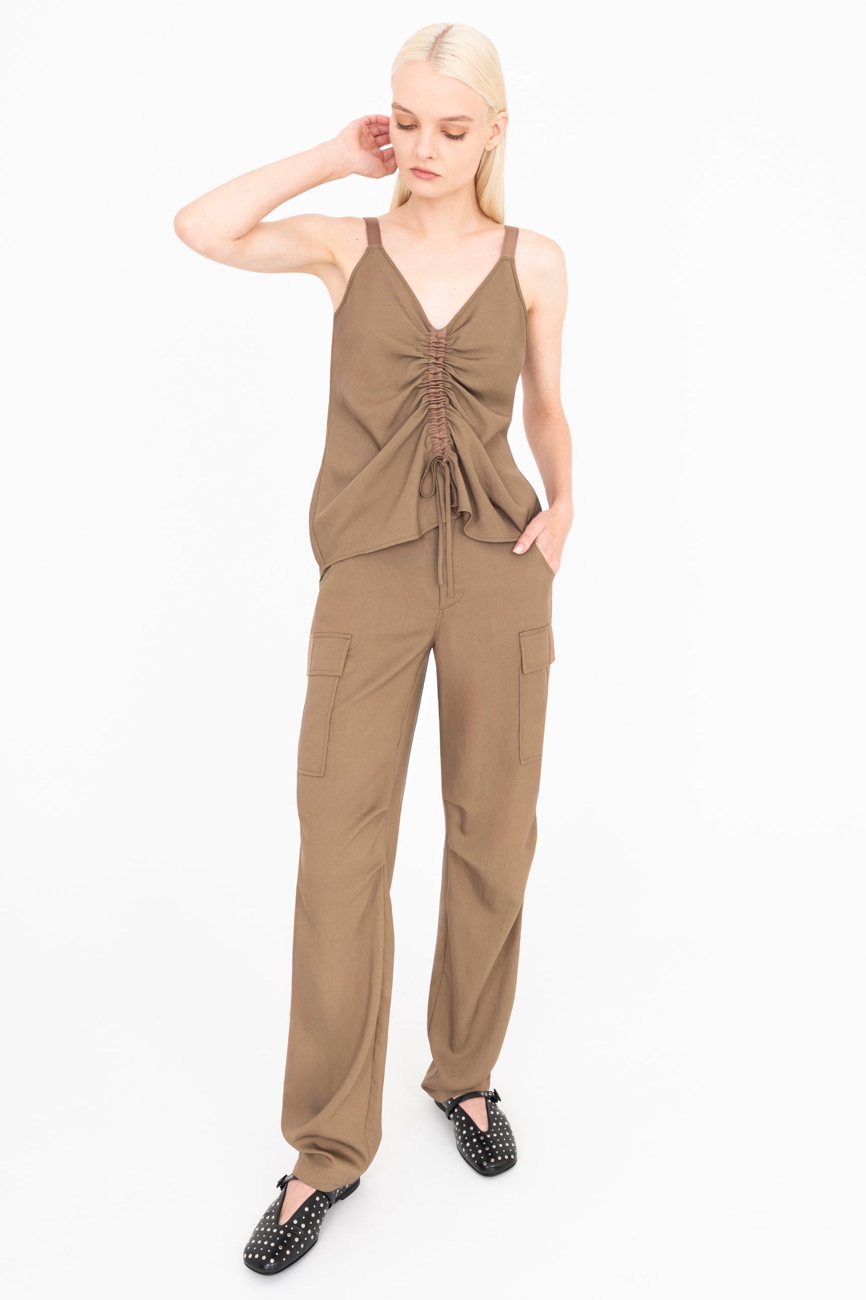 Woman wearing a brown camisole and pants on a white background