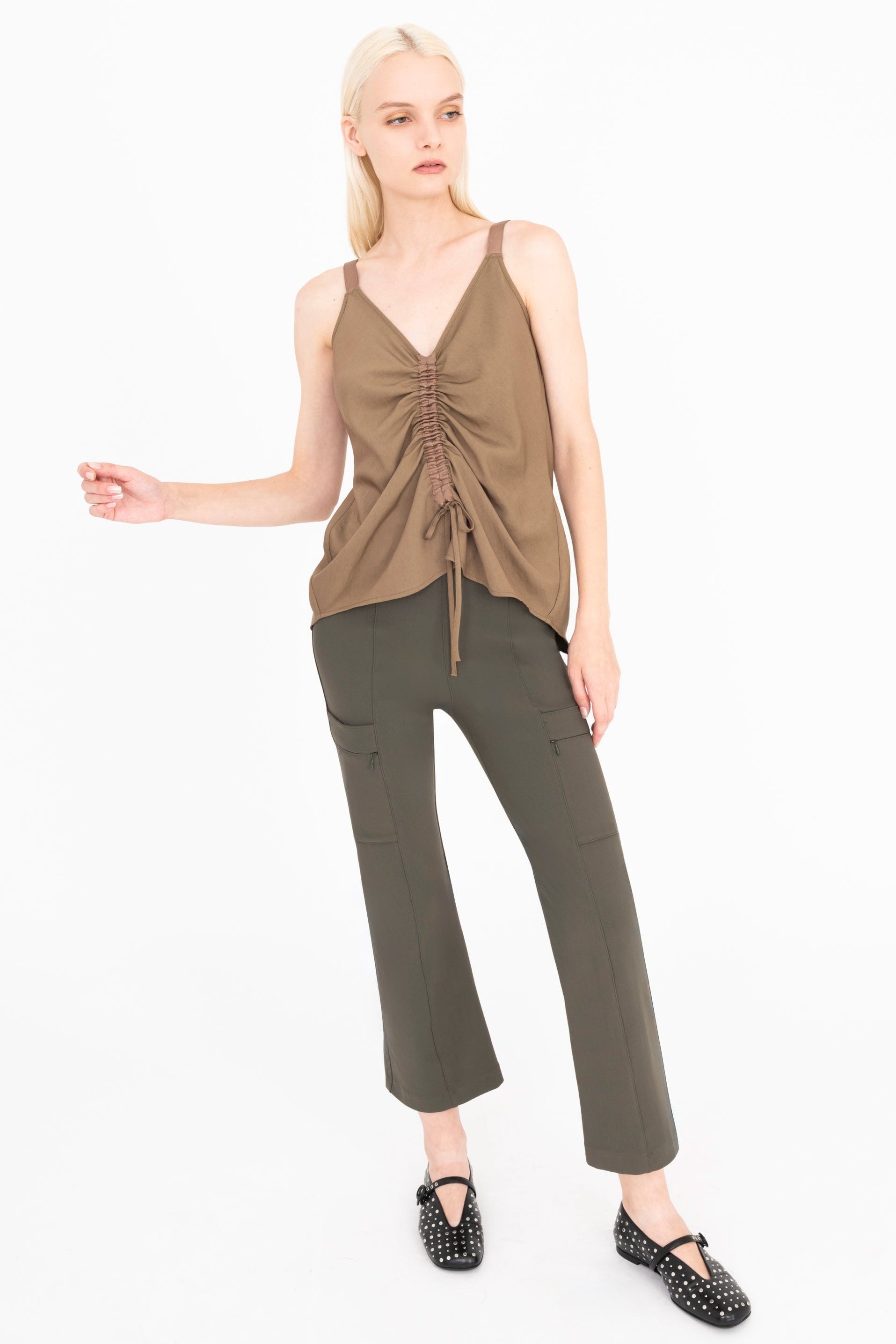 Woman wearing a brown top and green pants on a white background