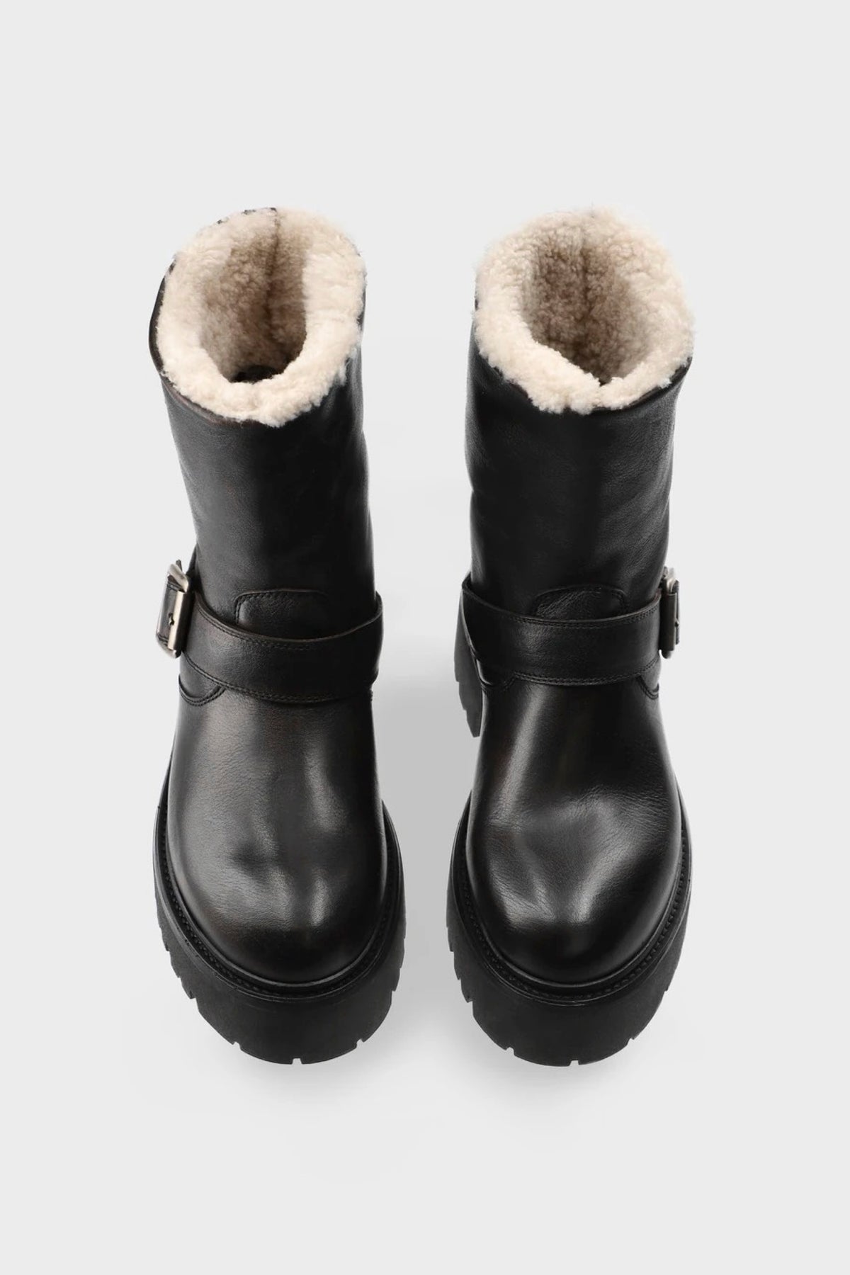 A pair of dark brown leather ankle boots with a thick platform sole and a cream-colored shearling lining, shown from a top-down view on a light gray background.