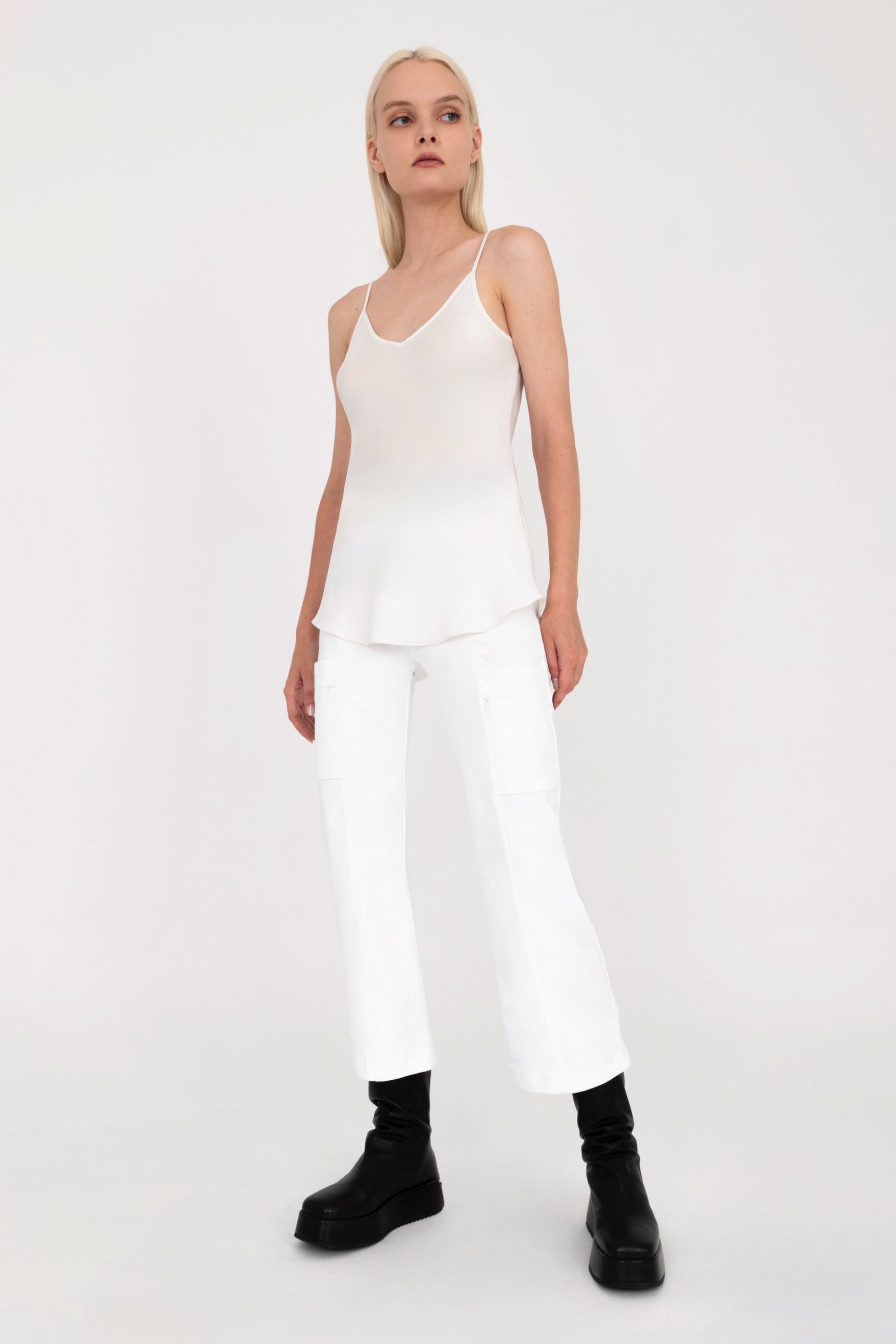 Woman wearing a white tank top and pants on a white background