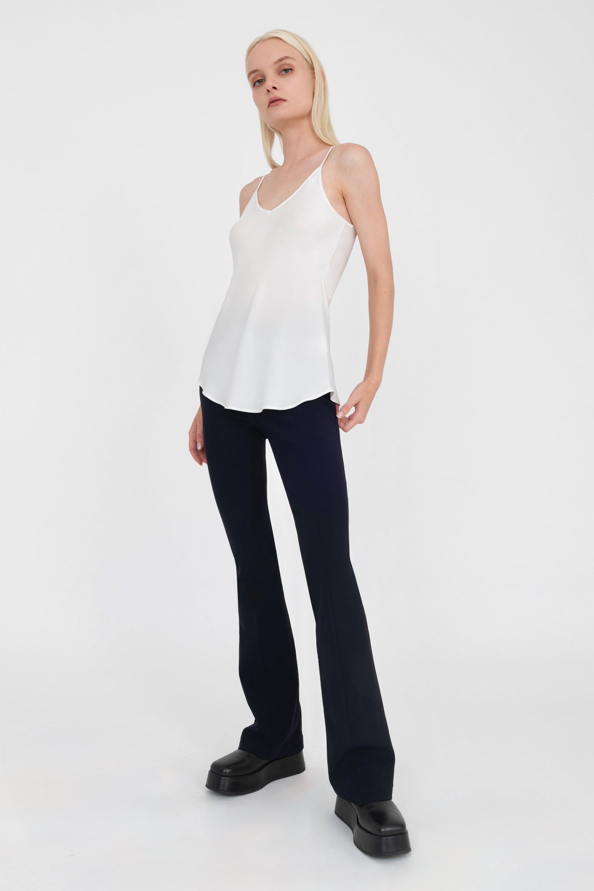 Woman wearing white top and black pants on a white background